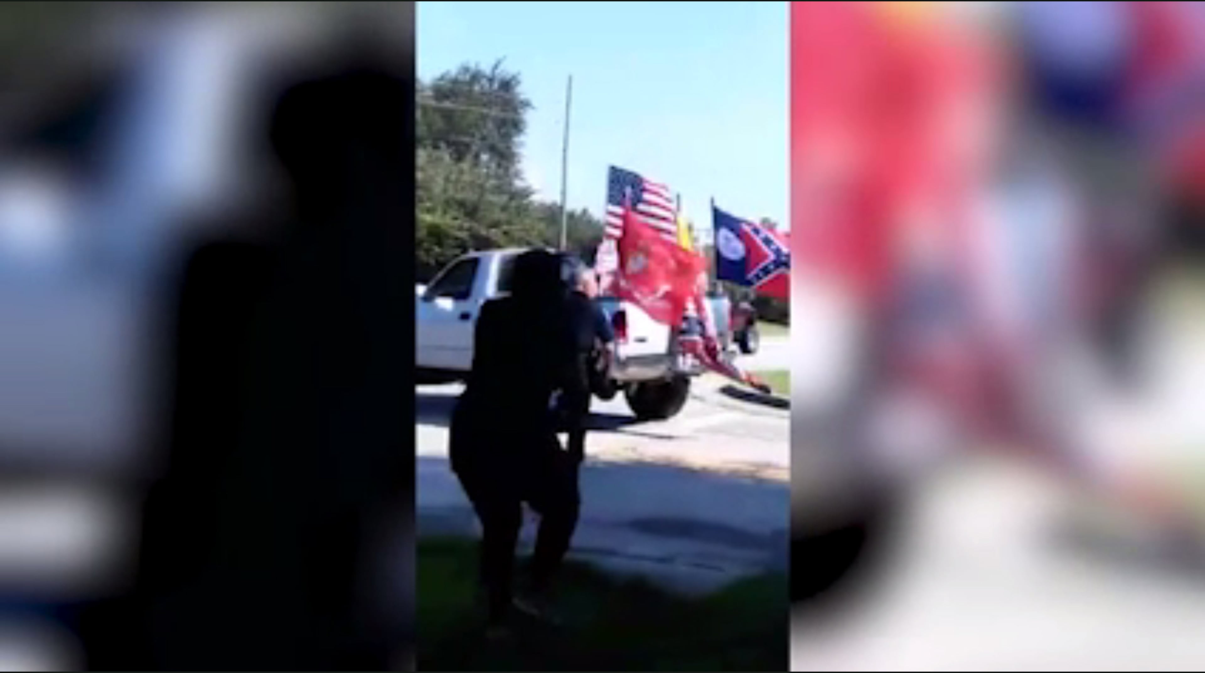 In this image from a phone video, trucks decked out with Confederate flags leave an area where the "Respect the Flag" group intimidated a black eight-year-old's birthday party next door. Police were on hand to see that the group was removed.