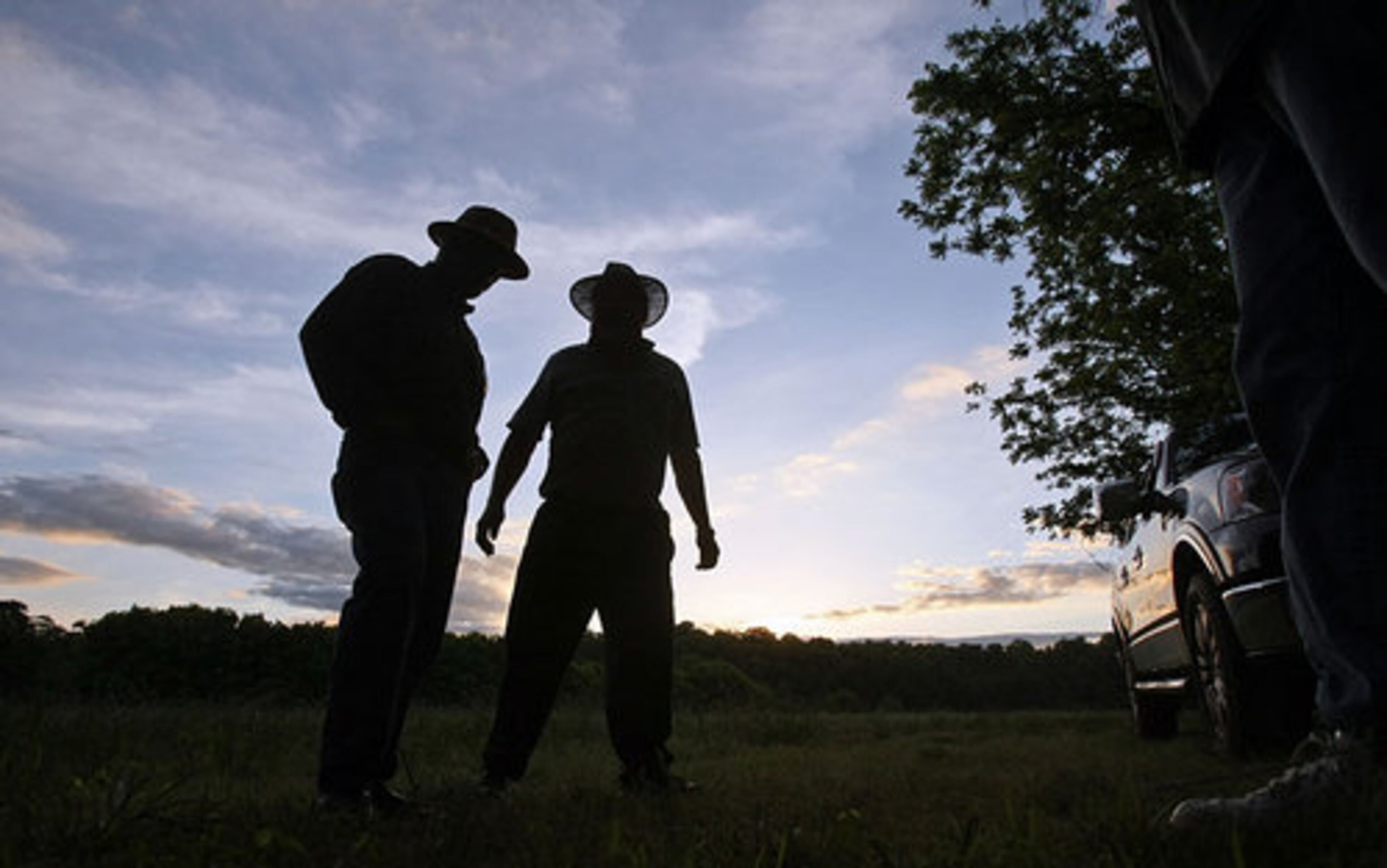 Smith, left, talks with Doug Michael, 69, center, as the sun sets. Michael is the father of guide Eddie Michael.