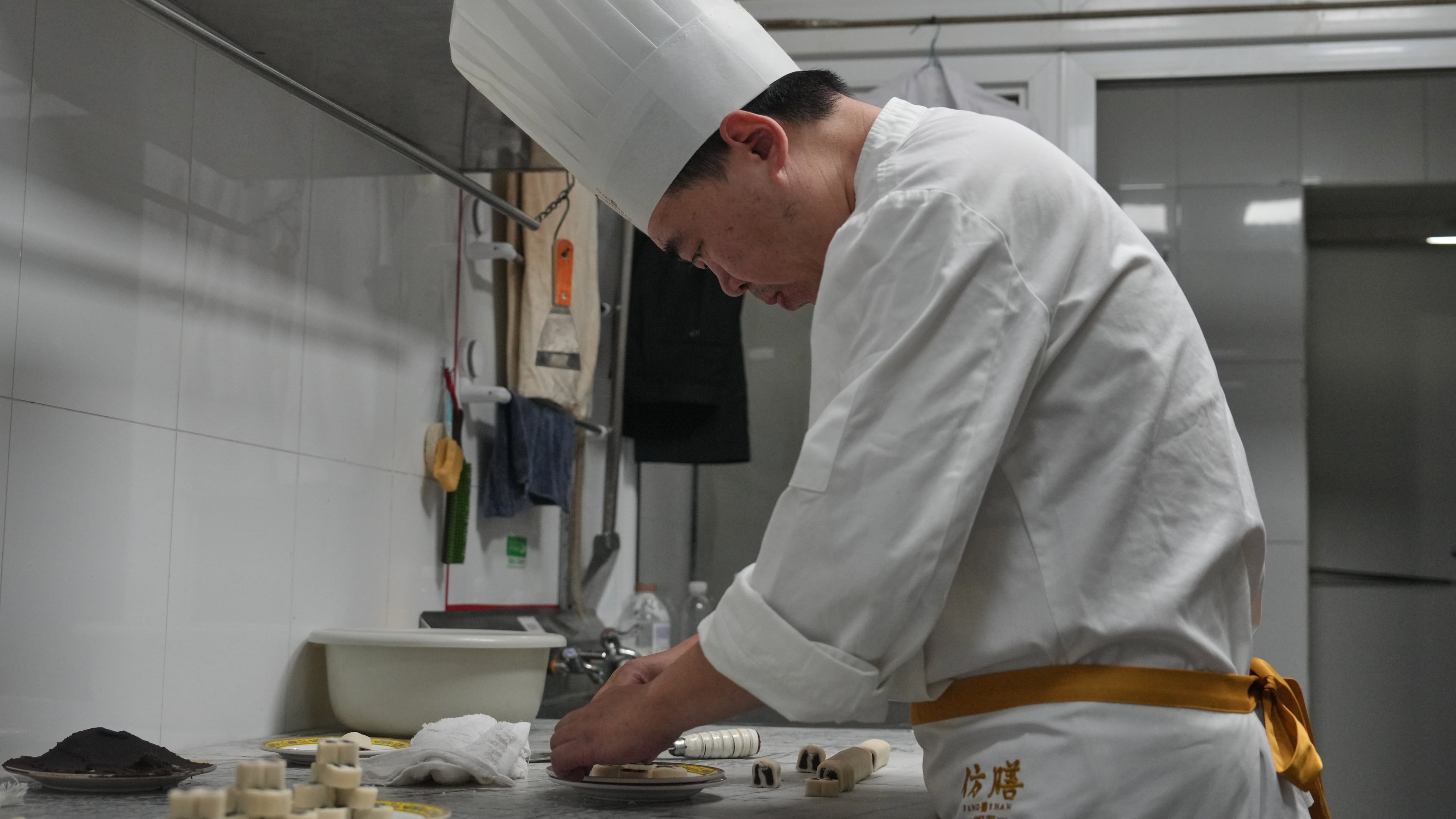 Chef Zhou Tong makes the minced pork pancake at Fangshan Restaurant inside Beihai Park in Beijing on July 23, 2026. (AP Photo/Andy Wong)