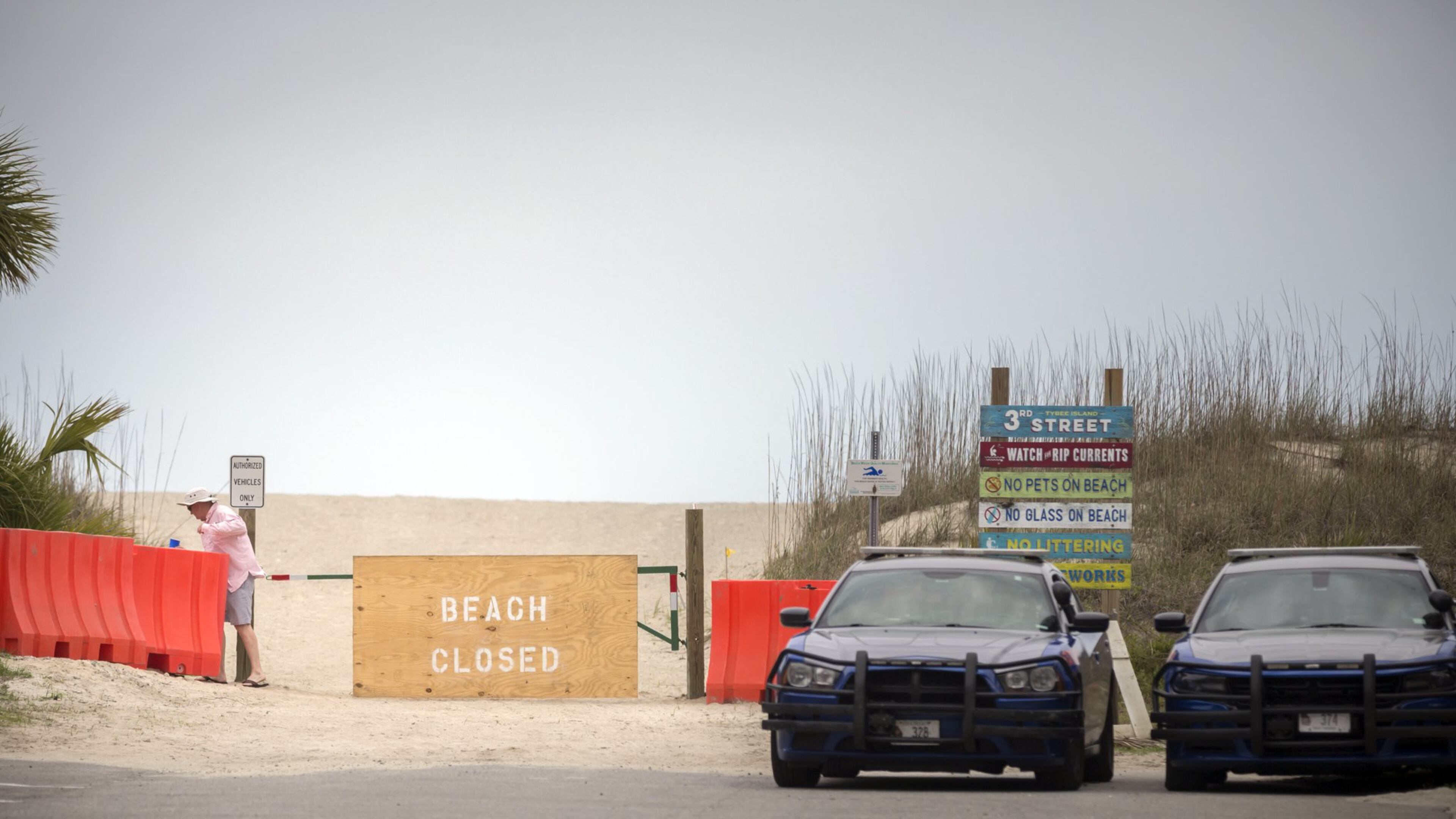A man squeezes through a barricade that blocks access to the beach on Tybee Island after he checked with Georgia State Patrol officers parked at the entrance on April 5. Gov. Brian Kemp signed an executive order to reopen the state’s beaches for exercise with social distance of at least 6 feet. (AJC Photo/Stephen B. Morton)