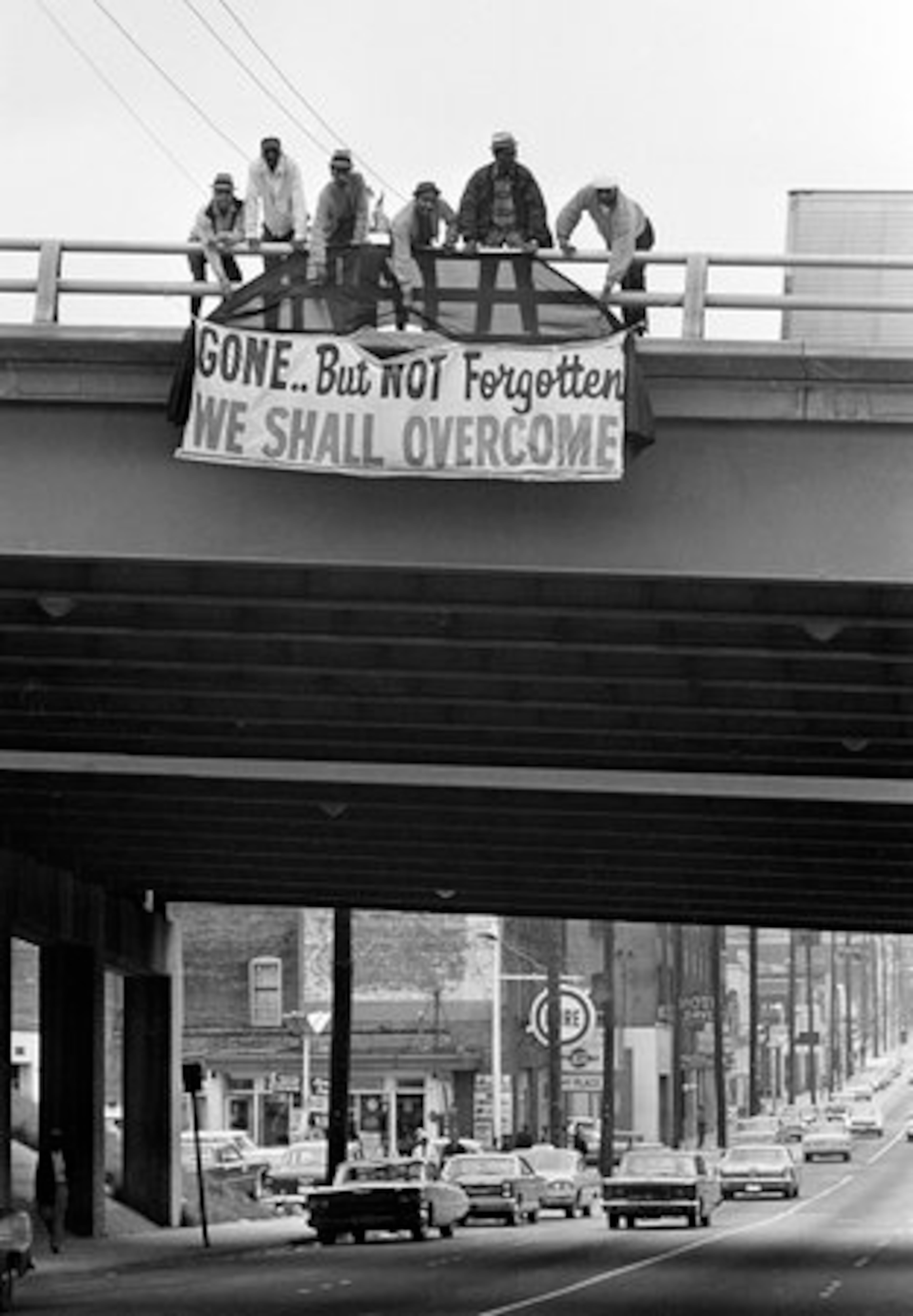 Six men hang a sign in honor of slain civil rights leader Dr. Martin Luther King, Jr. at an expressway bridge near King's Southern Christian Leadership Conference headquarters in Atlanta, April 8, 1968. Funeral services for King will be conducted Tuesday.