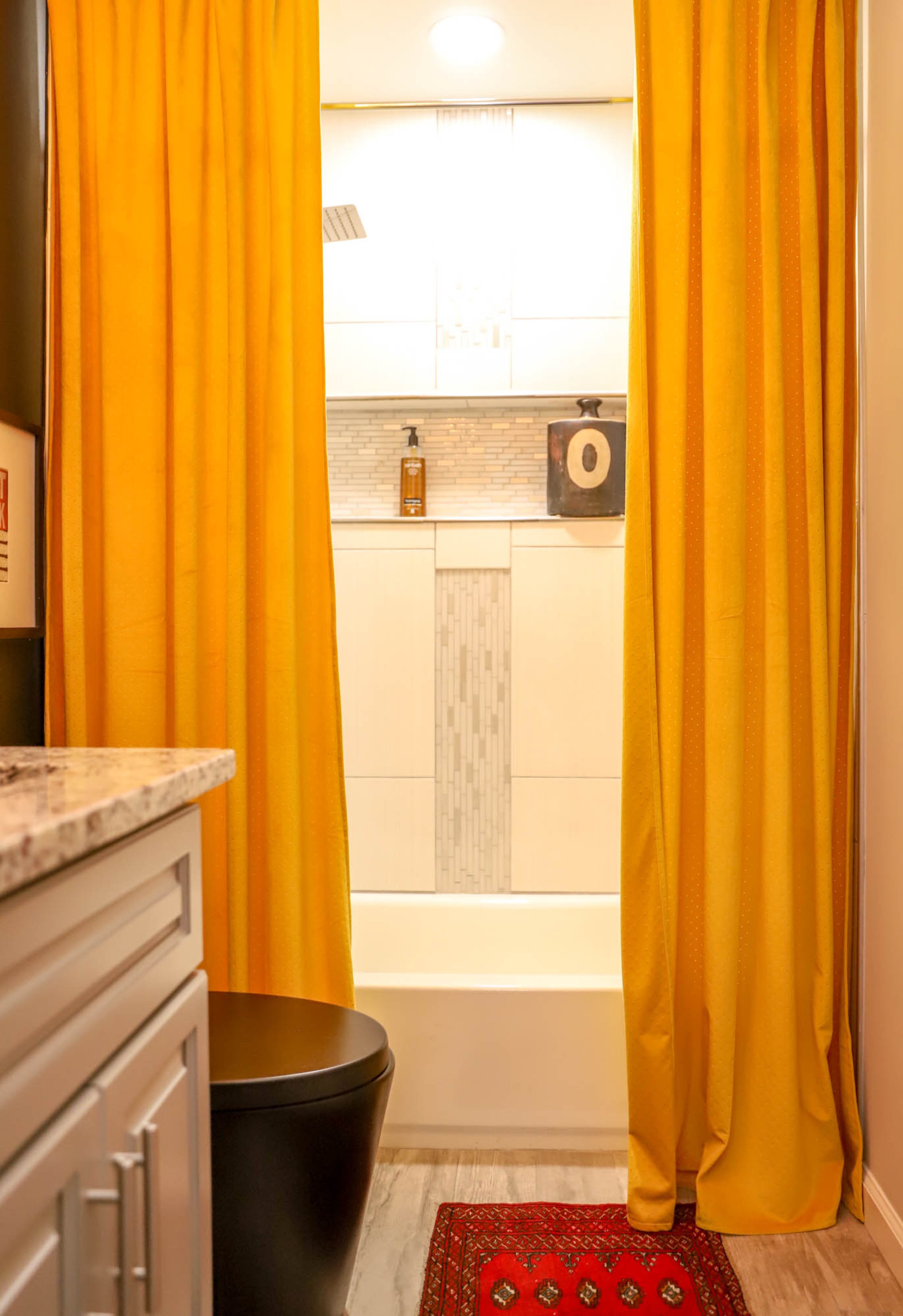 A black toilet from Wayfair and a pair of curtains from Anthropologie gives the guest bathroom of Vickie Pryor’s home a stylish contrast. Text by Shannon Dominy/Photo by Reynolds Rogers