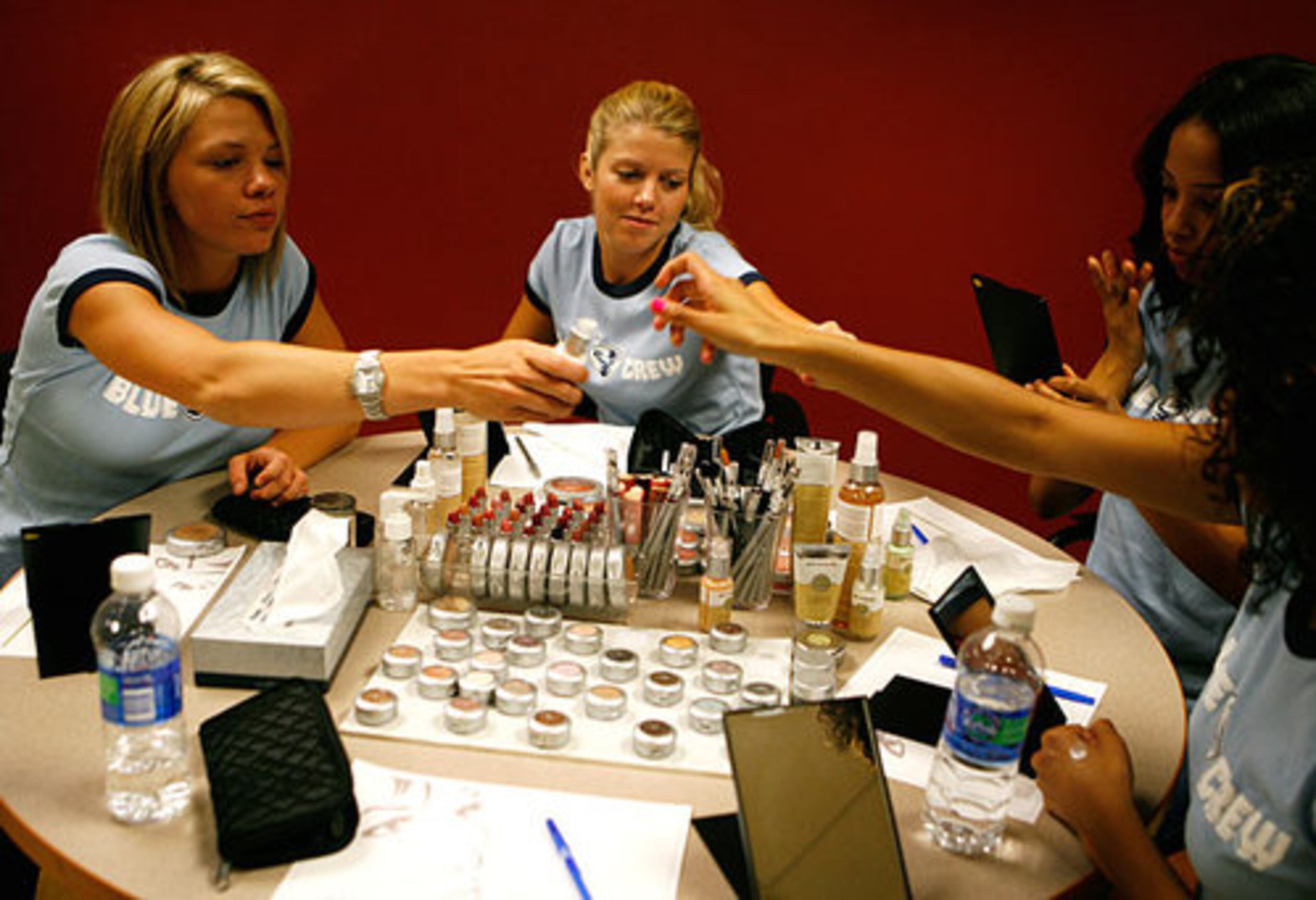 Blue Crew member Shea Allen (left) passes some makeup to fellow squad member Christina Zangas. Almost the entire crew showed up at the makeup company office to learn about the company's products and how to best apply them for gameday.
