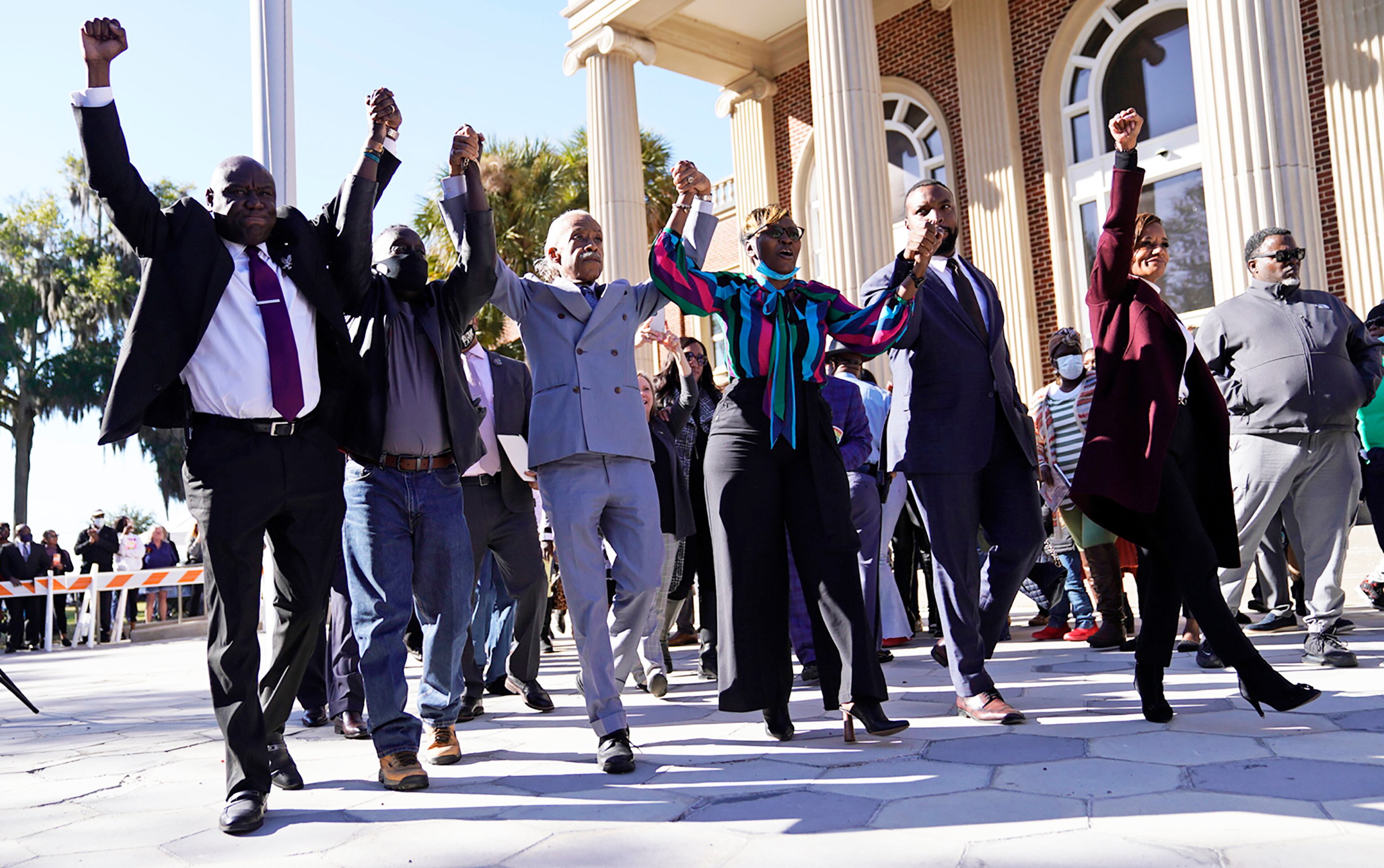 The Rev. Al Sharpton, third from the left, holds hands with Ahmaud Arbery’s parents, Wanda Cooper-Jones, right, and Marcus Arbery, left, as they react outside the Glynn County Courthouse in Brunswick, Ga., on Wednesday, Nov. 24, 2021, after the jury found three men guilty of murder and other charges for the pursuit and fatal shooting of Ahmaud Arbery. (Nicole Craine/The New York Times)