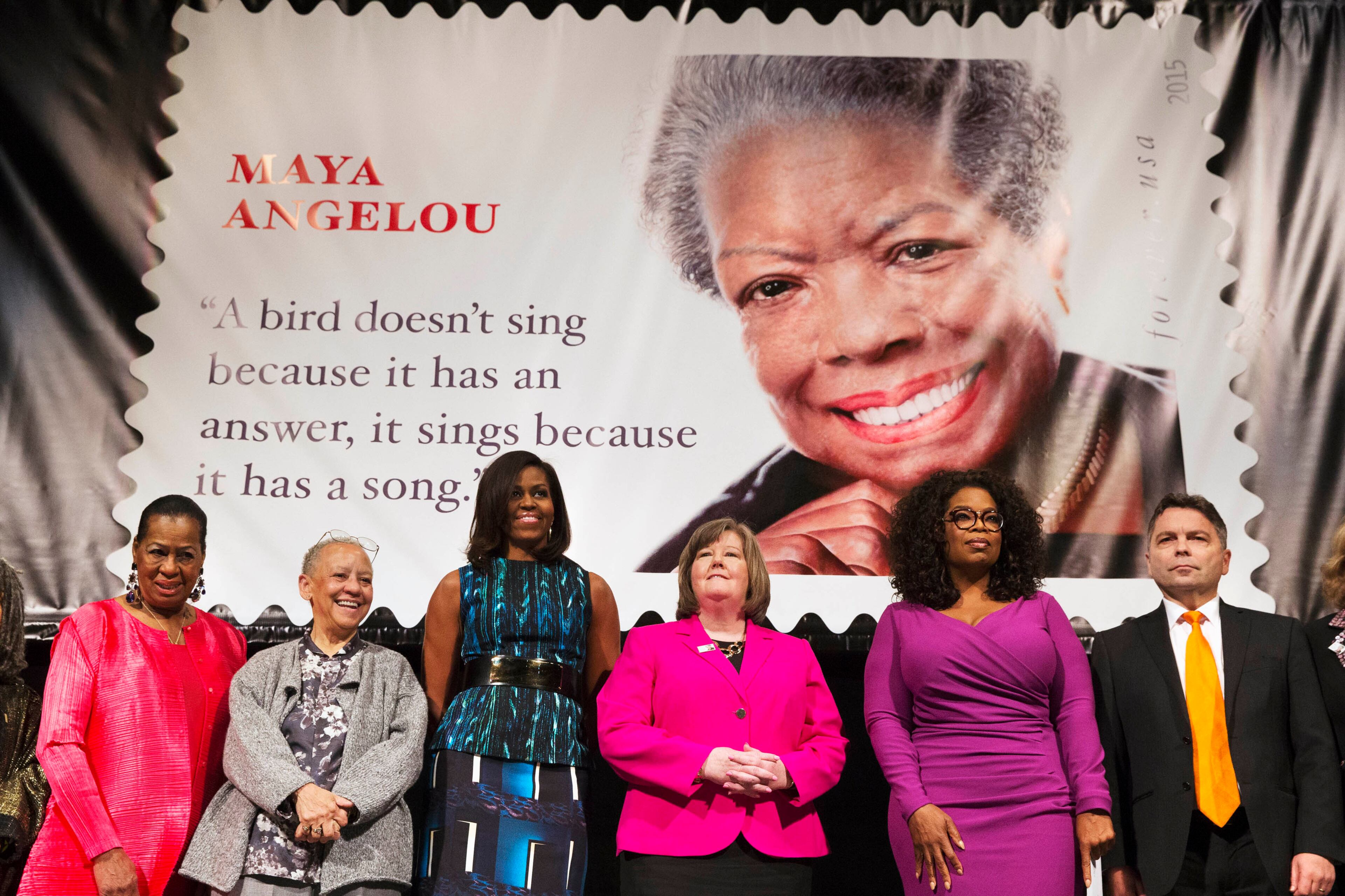 First lady Michelle Obama participates in the unveiling of the Maya Angelou Forever Stamp, Tuesday, April 7, 2015, at the Warner Theater in Washington. From left are, Eleanor Traylor, English Professor at Howard University; poet Nikki Giovanni; Mrs. Obama; Postmaster General Megan Brennan; Oprah Winfrey, and artist Ross Rossin. (AP Photo/Jacquelyn Martin)