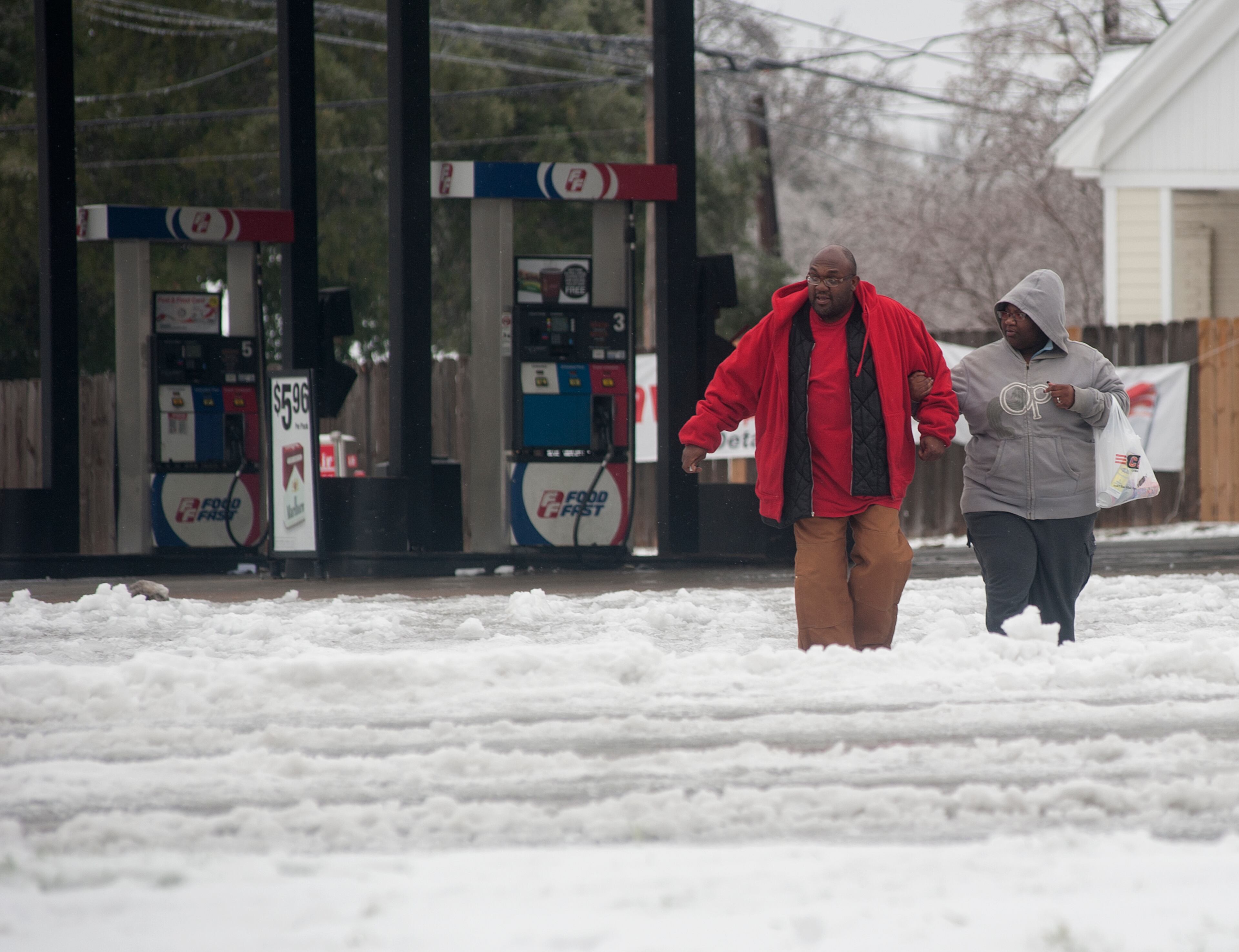 Henry King and Nashonda Johnson lock arms as they cross a very icy S. Palace Ave. Tyler, Texas on Monday, March 3, 2014. The Texas Department of Public Safety says interstate traffic in North and East Texas is moving slowly after sections were closed because of multiple accidents caused by icy conditions. DPS Sgt. Lonny Haschel said Monday the concern is the interstates refreezing as temperatures in North Texas are expected to fall into the 20s overnight. Traffic on Interstate 45 south of Dallas on Sunday night and into Monday was at a virtual standstill for hours as accidents and tractor-trailers unable to climb steep grades blocked other vehicles. (AP Photo/The Tyler Morning Telegraph, Sarah A. Miller)