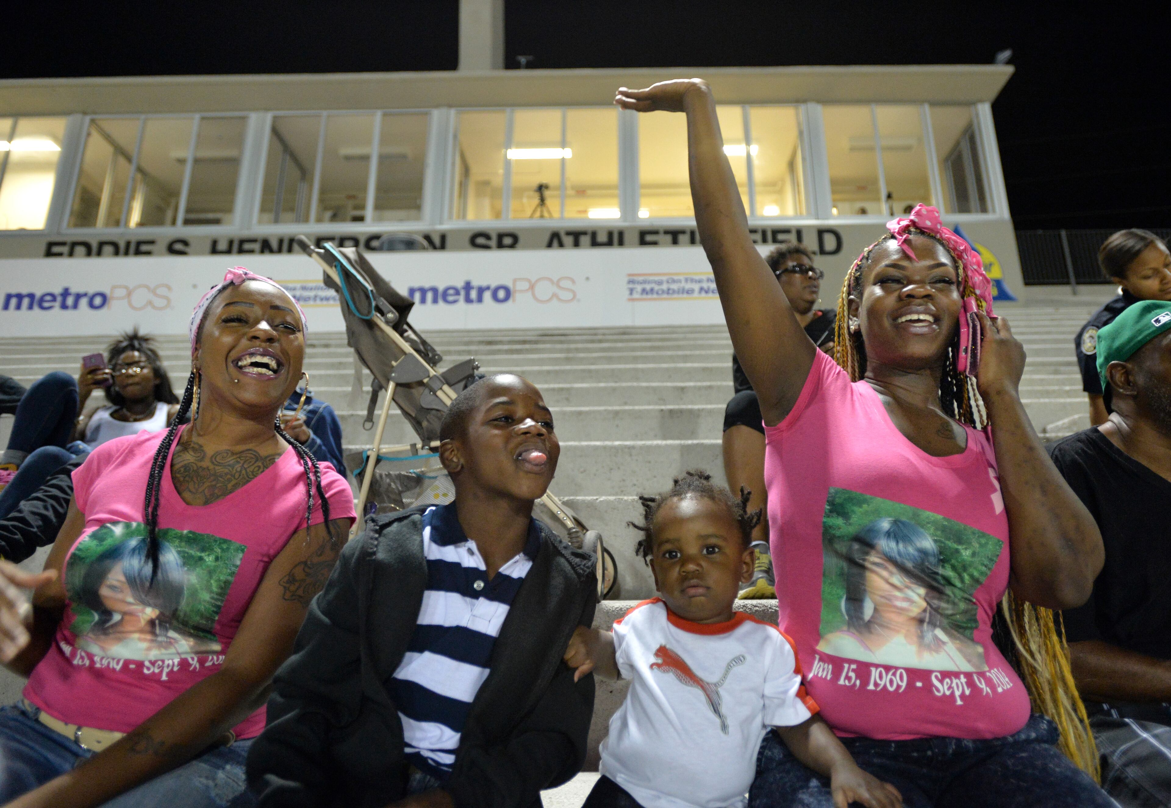 Ashley Roberson (right), 23, waves to her brother Darius Marshall, 18, with (from left) her best friend Jaisharia Billings, younger brother Damyuss Marshall, 8, and son Demetrius Broadnax Jr., 1, during B.E.S.T Academy football game against the Wesleyan school at Grady High School stadium on Friday, October 10, 2014. HYOSUB SHIN / HSHIN@AJC.COM