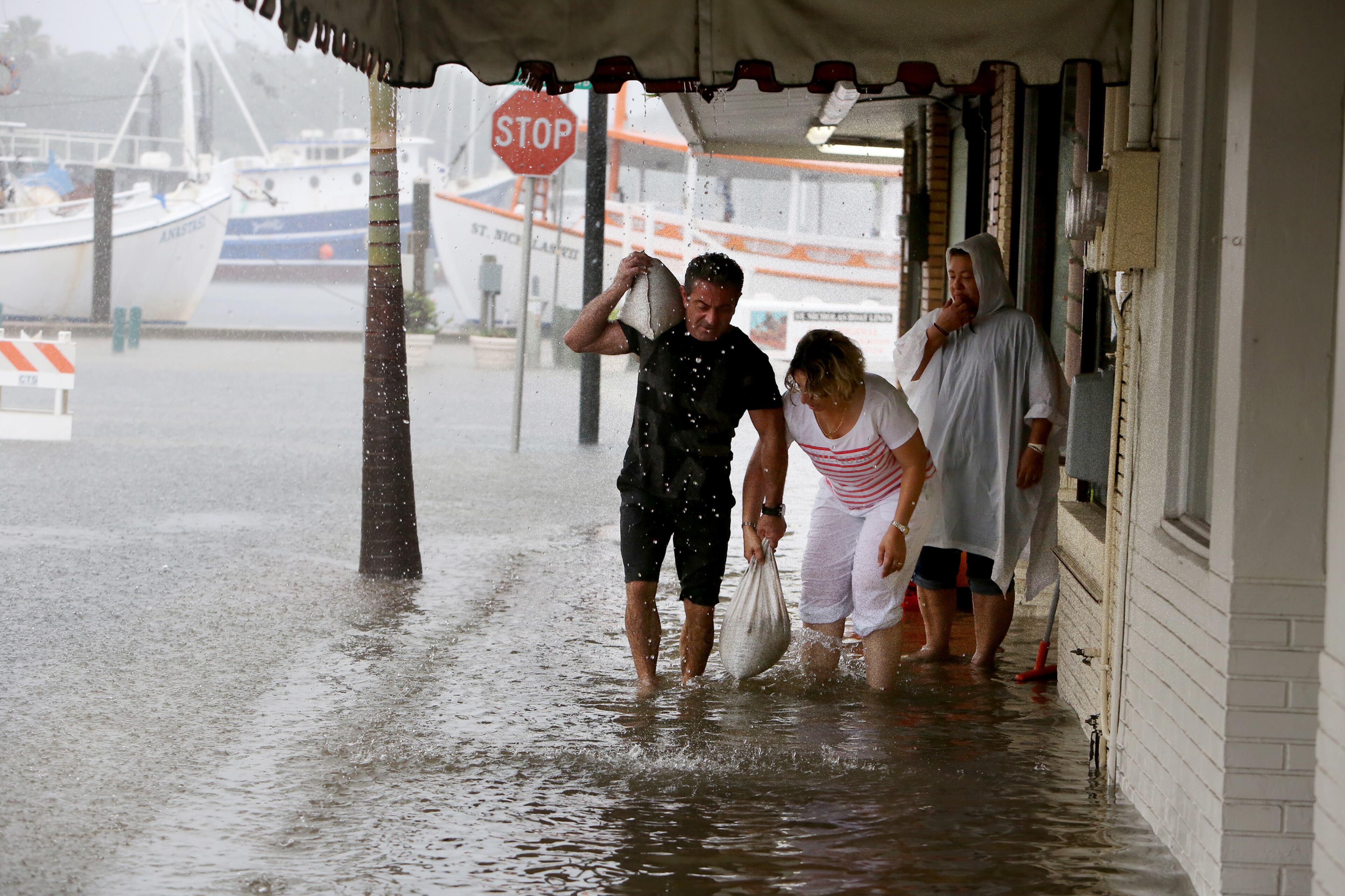 Angelo Memiakis, left, and Kelly Spiliotis work to deliver sandbags to the door jams of businesses along flooded Athens Street on Monday, June 6, 2016, in Tarpon Springs, Fla., as Tropical Storm Colin barreled up the west coast of Florida. Residents on Florida's Gulf coast filled sandbags, schools closed early and graduation ceremonies were postponed as Gov. Rick Scott declared a state of emergency with Tropical Storm Colin churning toward the state Monday, threatening serious flooding. (Douglas R. Clifford/The Tampa Bay Times via AP) TAMPA OUT; CITRUS COUNTY OUT; PORT CHARLOTTE OUT; USA TODAY OUT; BROOKSVILLE HERNANDO TODAY OUT; MANDATORY CREDIT