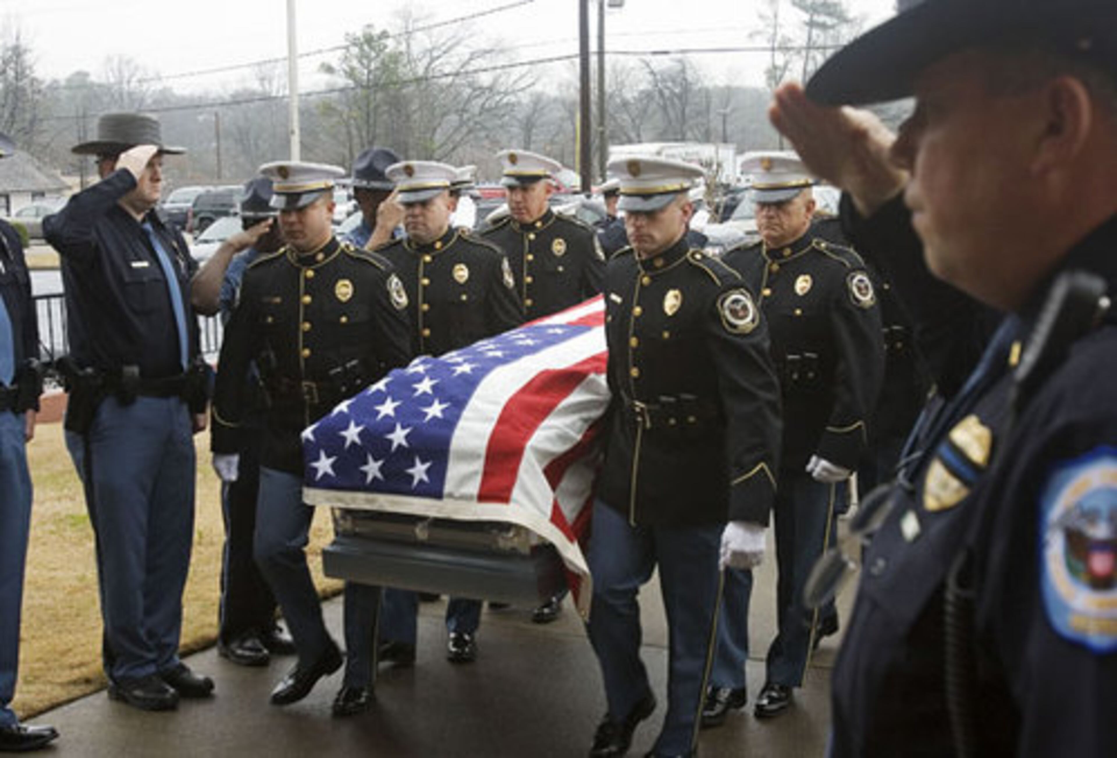 Public safety officers salute as the honor guard carries Norman's casket into the church for the funeral.