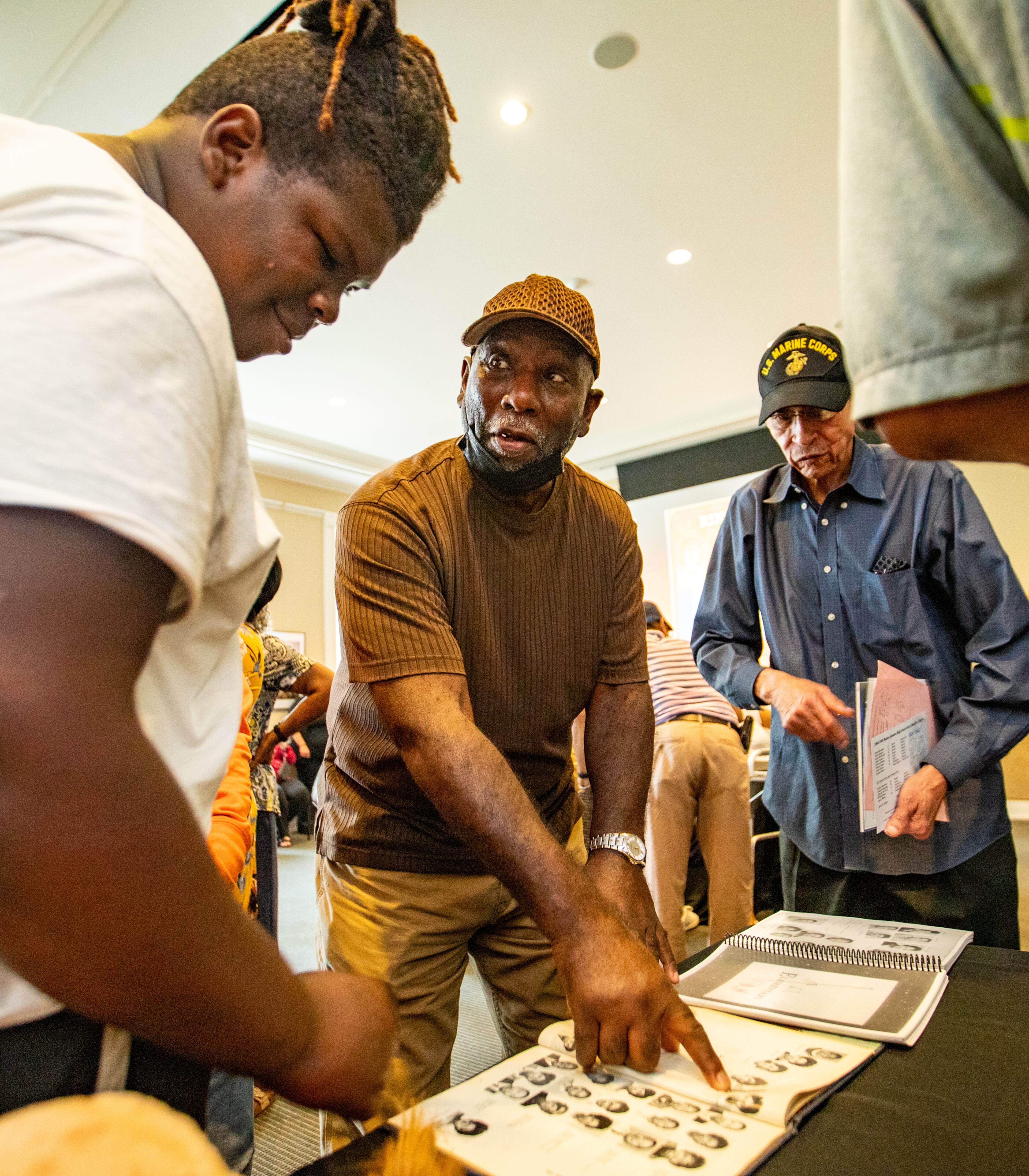 Trenton Kennemore, left, takes a look at his grandfather’s Bailey-Johnson High School photo. His grandfather Almond Martin, center, and James Emerson were on the 1964-65 basketball team and were presented with their State Championship rings on Monday during the Alpharetta City Council meeting. (Jenni Girtman for The Atlanta Journal-Constitution)