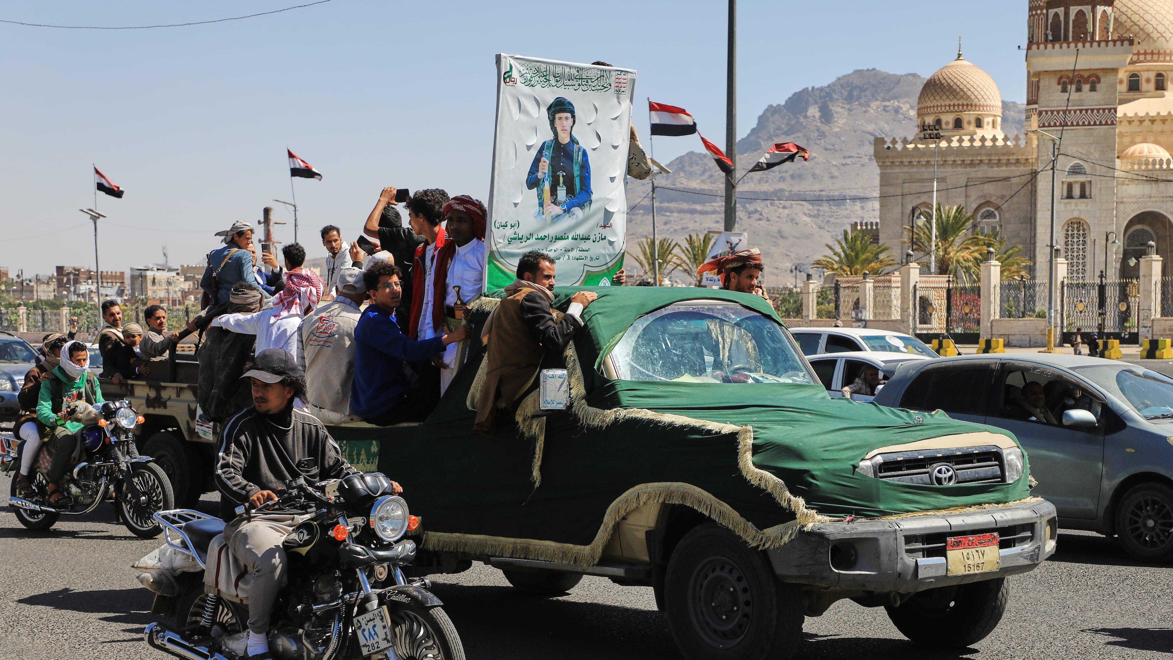 People ride in a pickup truck during a funeral procession for a Houthi officer in Sanaa, Yemen, Saturday, Oct. 17, 2026. The Arabic banner reads, "Martyr Mazen Abdallah." (AP Photo/Osamah Abdulrahman)
