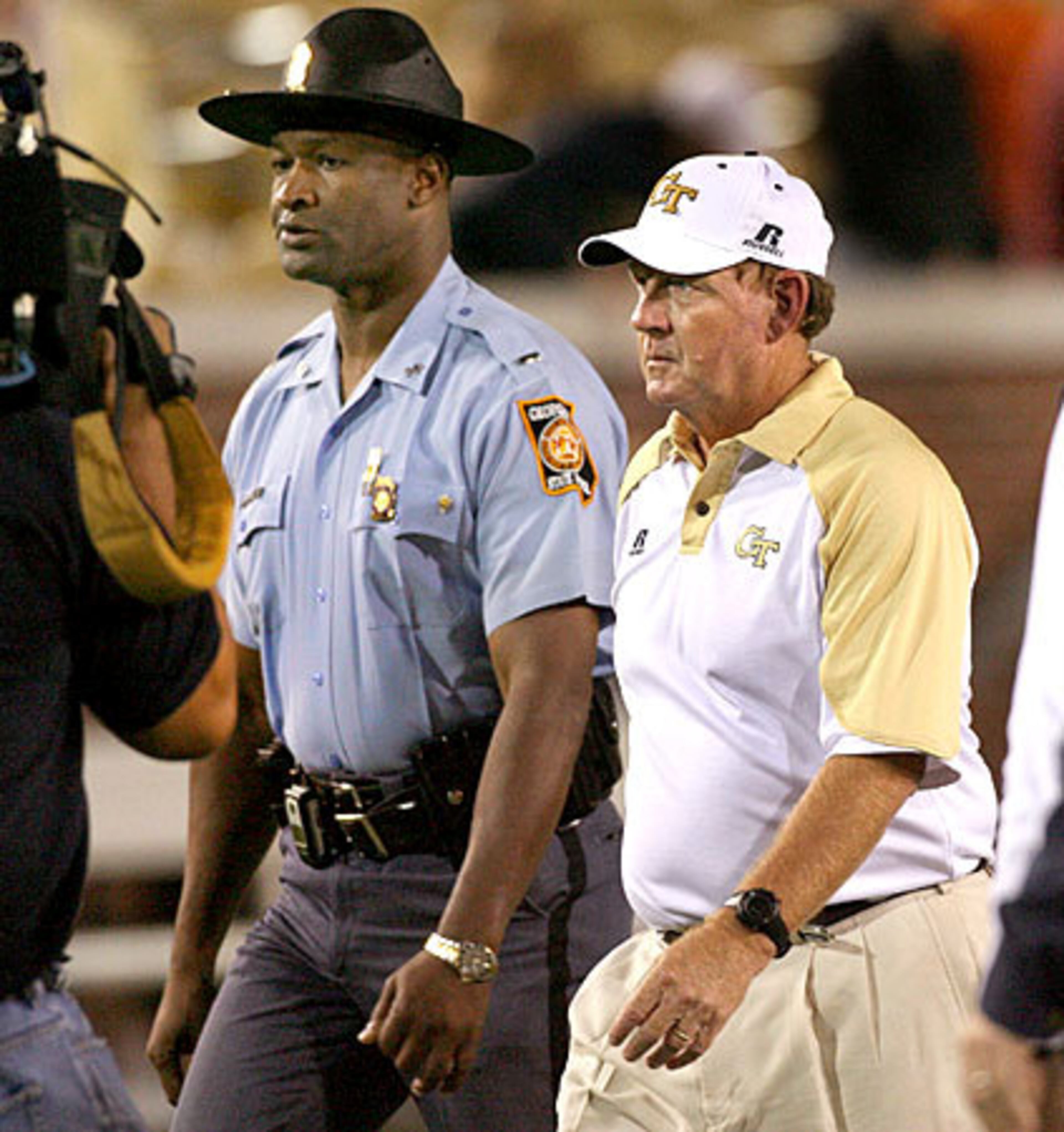 Georgia Tech's coach Chan Gailey walks off the field while being escorted by a Georgia State Patrol officer.