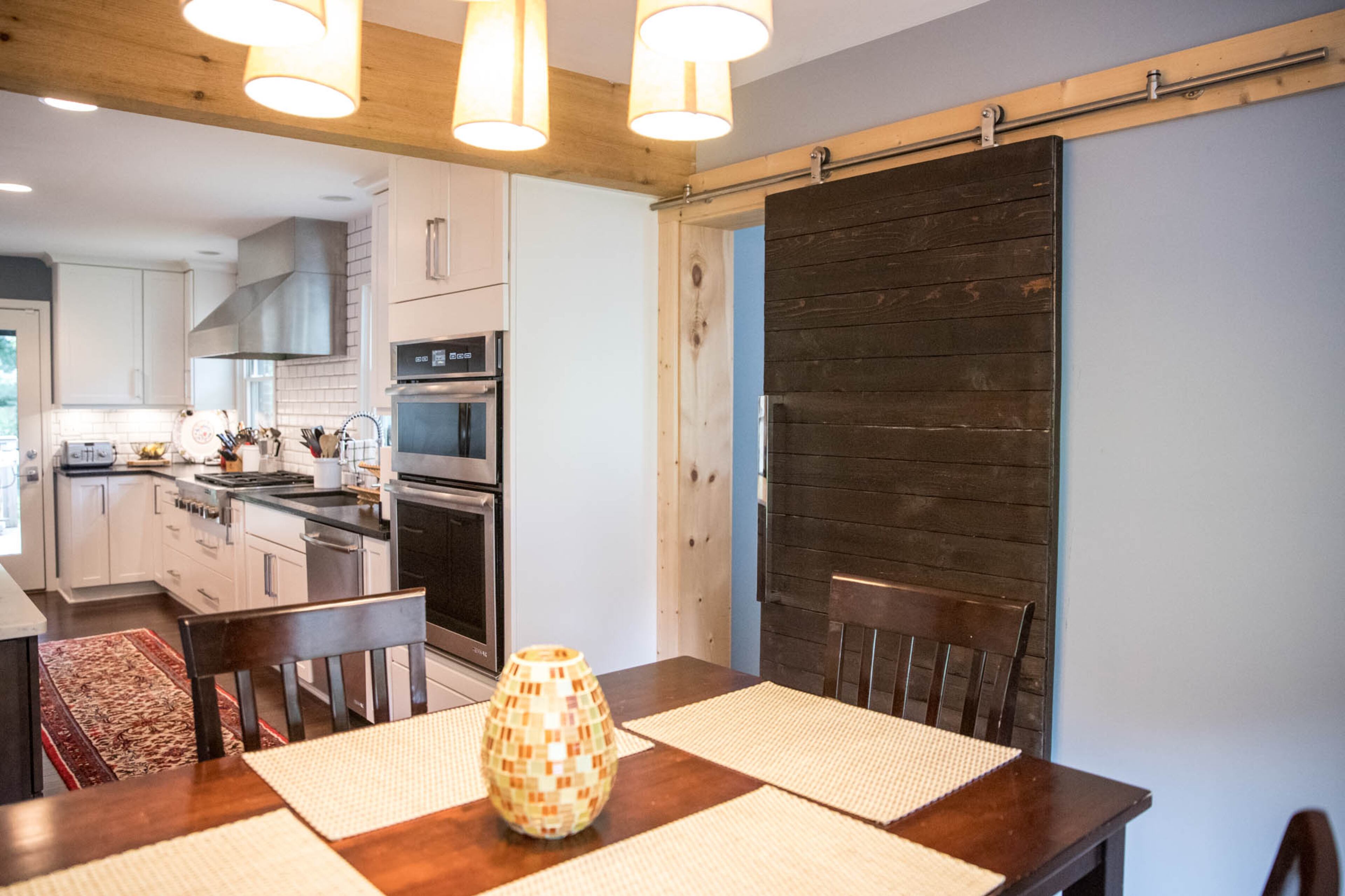 A custom barn door by Jessica Murphy of Her Cave Atlanta provides a compact and stylish way for Adam Perry and Ben Ratossa to close off the breakfast nook in their kitchen.