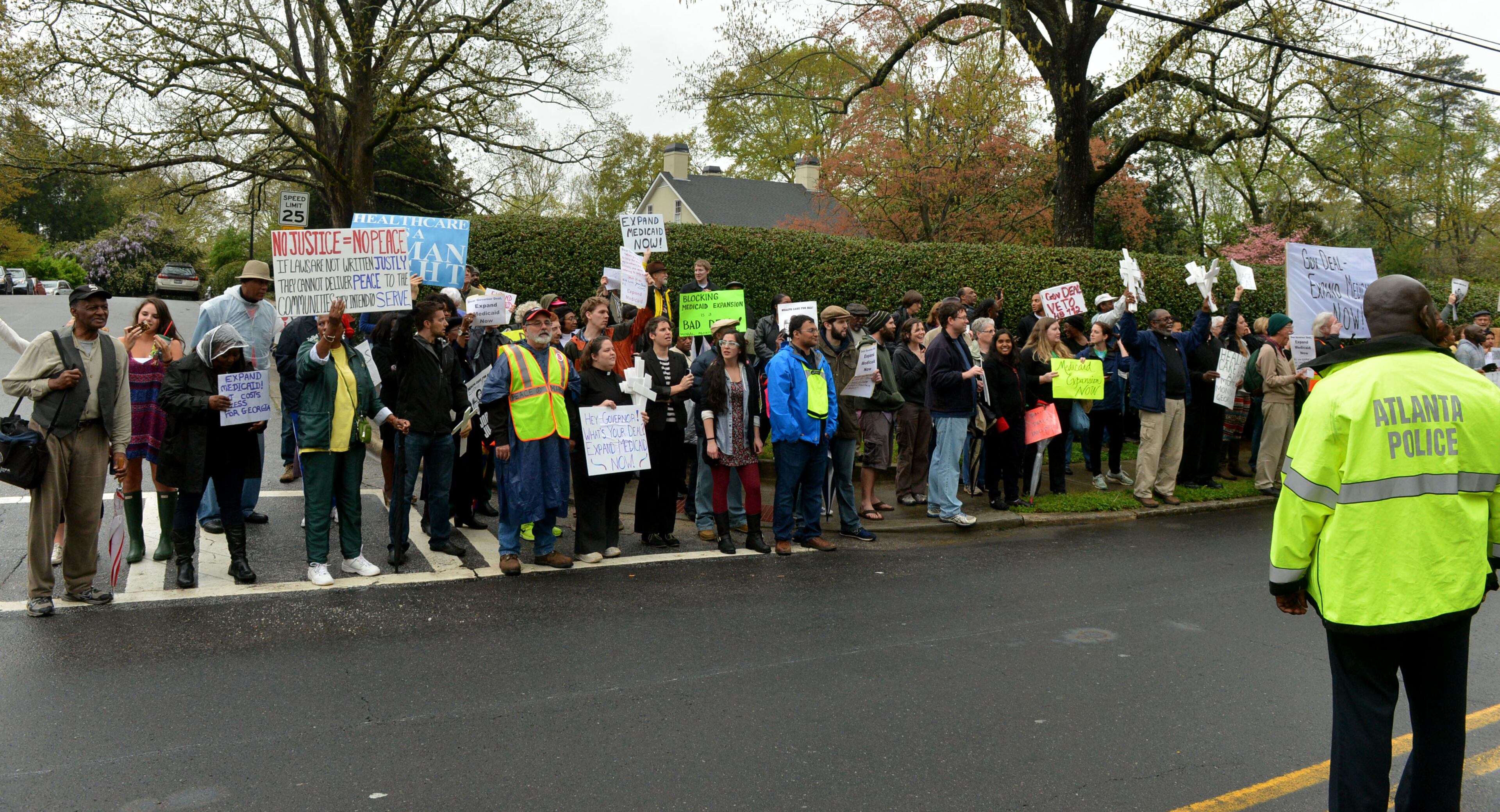 A crowd that swelled to over 100 protesters including several Atlanta clergy members and officials joined with Moral Monday in a Medicaid expansion rally outside the Governor's Mansion on W. Paces Ferry Road Monday, April 7, 2014. Protesters were calling on Governor Nathan Deal to expand Medicaid services in the state. KENT D. JOHNSON / KDJOHNSON@AJC.COM