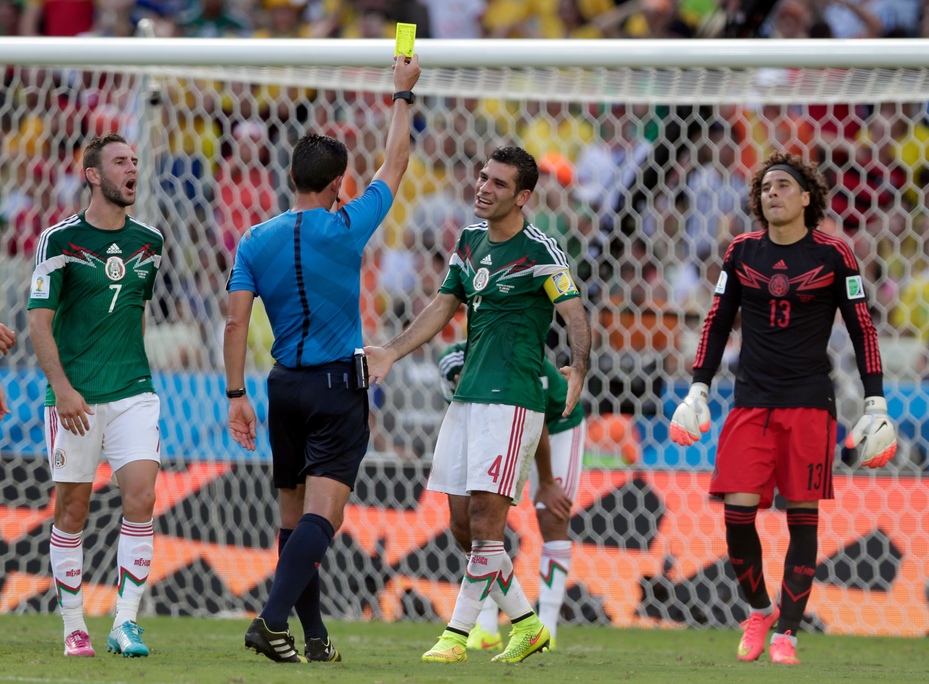 Referee Pedro Proenca from Portugal shows a yellow card to Mexico's Rafael Marquez, 2nd right, after a penalty while Mexico's goalkeeper Guillermo Ochoa, right, and Mexico's Miguel Layun, left, look on the World Cup round of 16 soccer match between the Netherlands and Mexico at the Arena Castelao in Fortaleza, Brazil, Sunday, June 29, 2014. At right is Mexico's goalkeeper Guillermo Ochoa . At left Mexico's Miguel Layun.(AP Photo/Marcio Jose Sanchez)