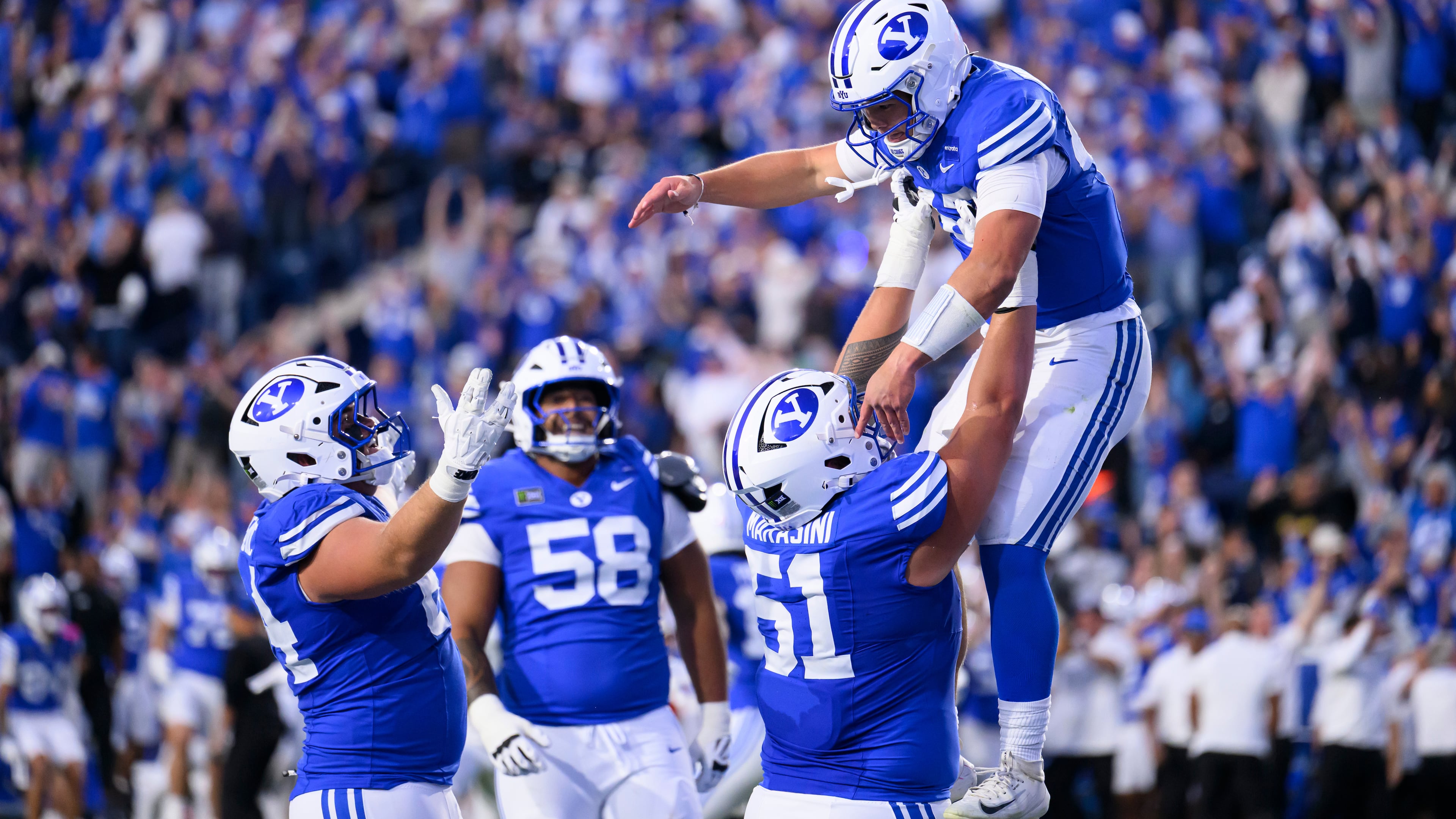 BYU offensive lineman Sonny Makasini, center right, lifts quarterback Bear Bachmeier, top, after Bachmeier ran for a touchdown during the first half of an NCAA college football game against Notre Dame, Saturday, Oct. 17, 2026, in Provo, Utah. (AP Photo/Tyler Tate)