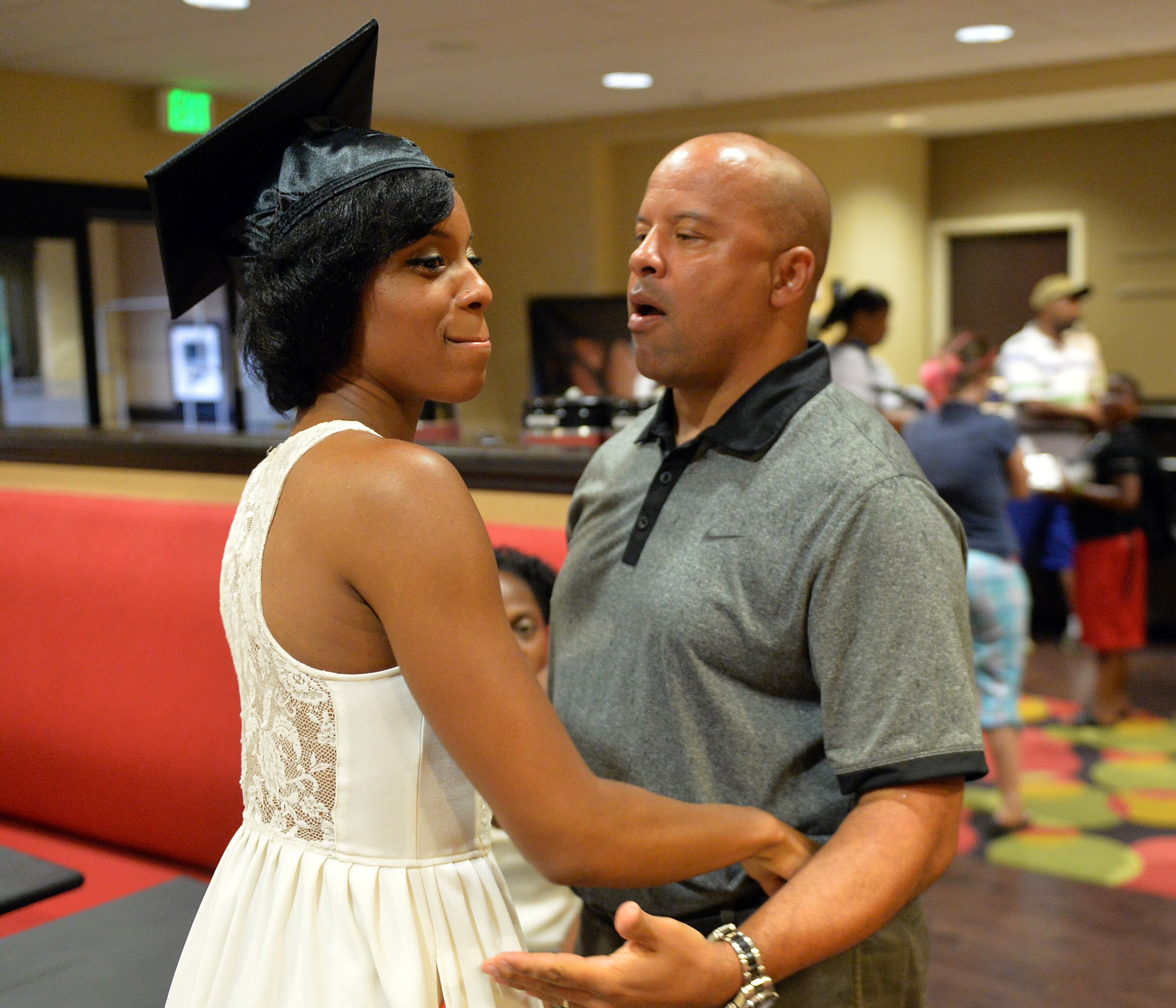 Tayla hugs her father, Vincent Washington. Members of the Washington family join together to celebrate the graduation of Tayla Washington, 23, at Jacksonville State University Friday, August 8, 2014. KENT D. JOHNSON / KDJOHNSON@AJC.COM