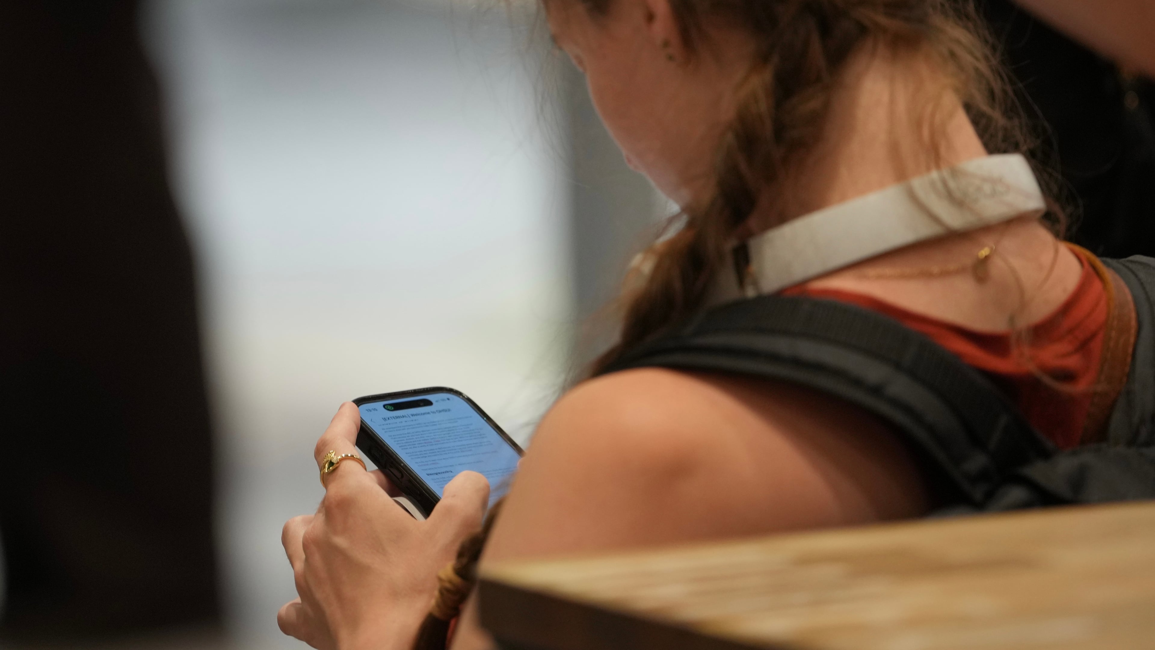 A teenager looks at her mobile phone in London, Monday, June 15, 2026. (AP Photo/Kin Cheung)
