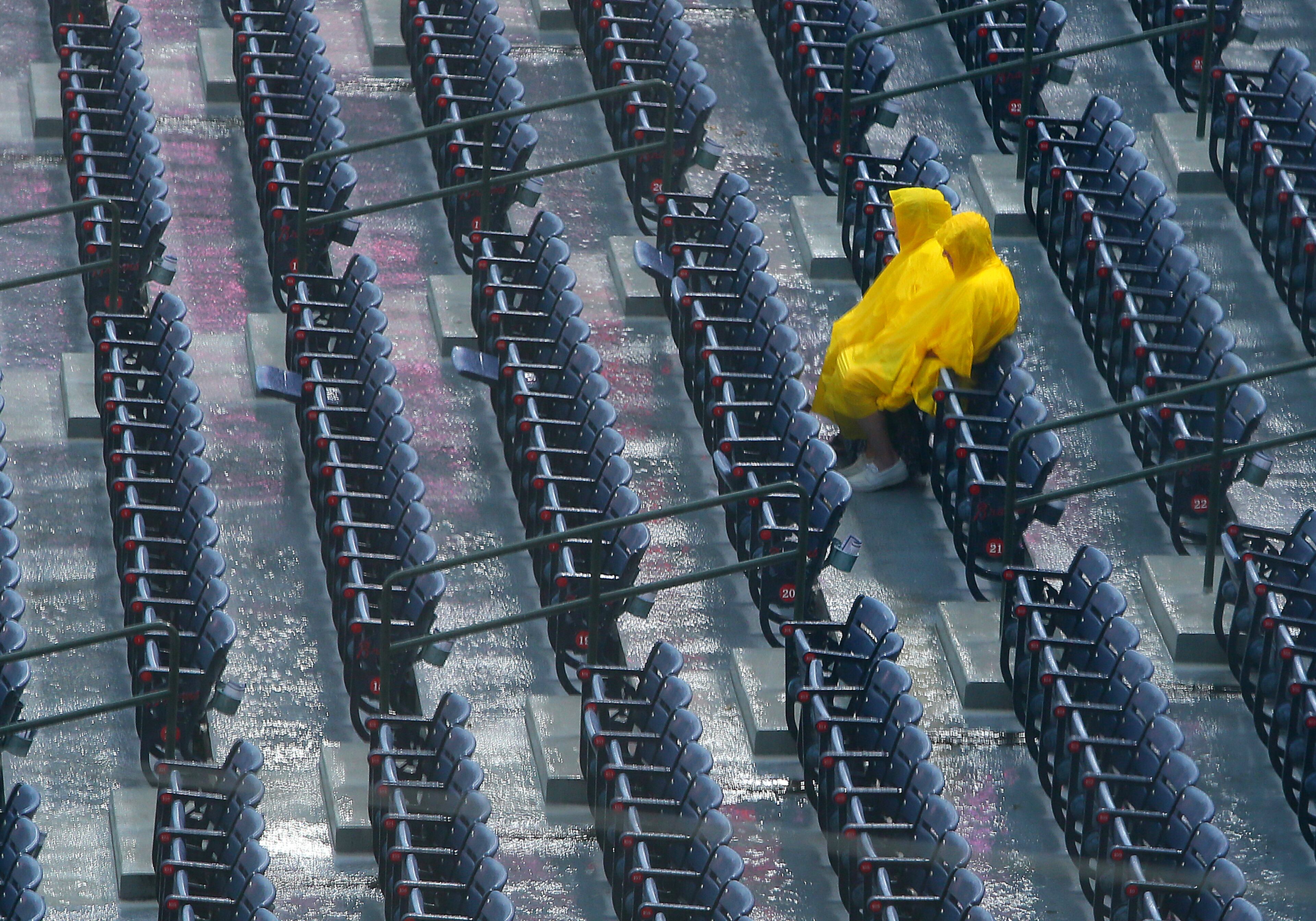 A pair of baseball fans wait out a rain delay at the Braves vs. Phillies MLB game at Turner Field on Monday, August 12, 2013, in Atlanta.