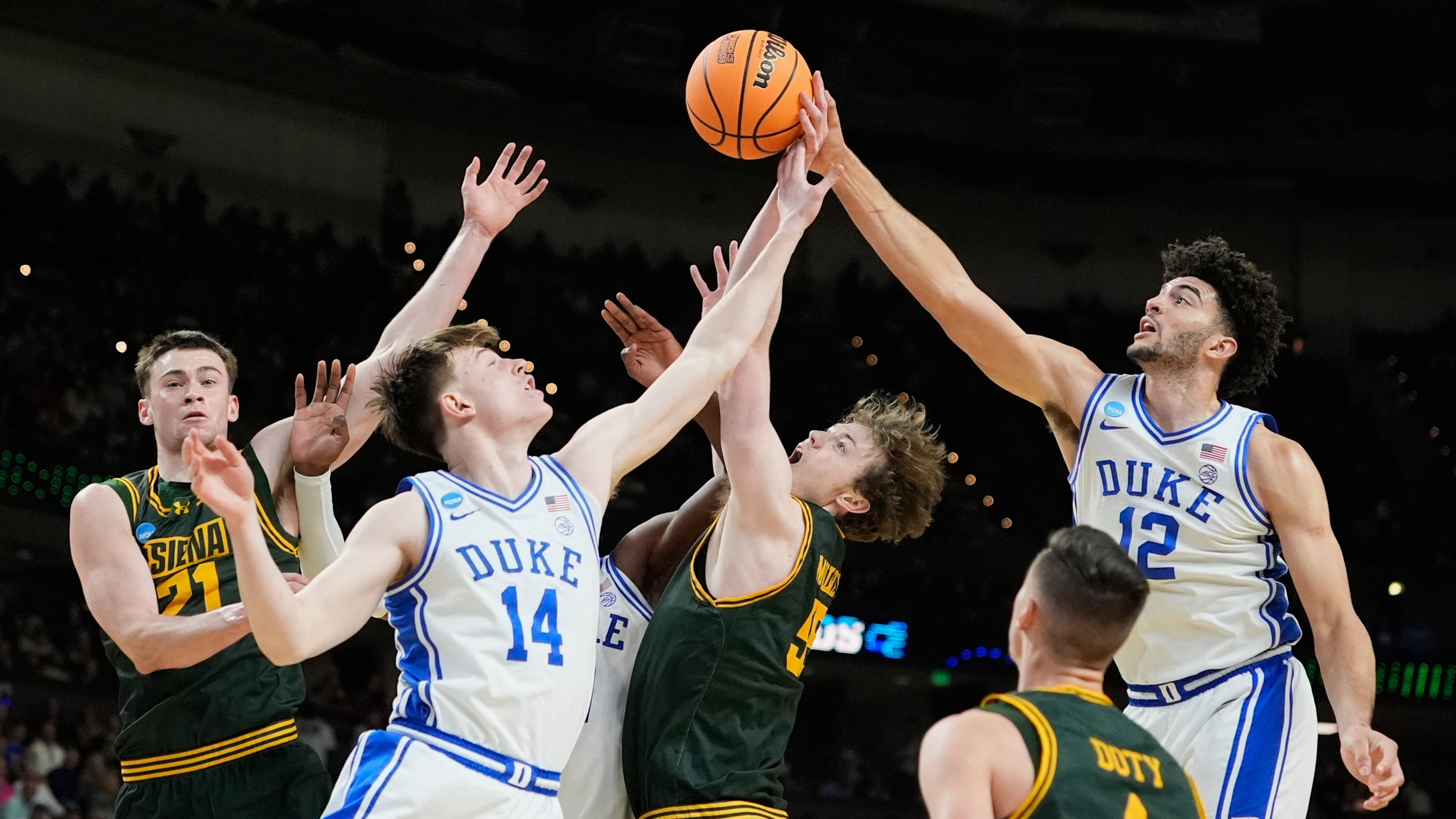 Duke's Cameron Boozer (12) and Nikolas Khamenia (14) battle for the ball with Siena's Riley Mulvey (55), Brendan Coyle (21) and Gavin Doty (4) during the first half in the first round of the NCAA college basketball tournament, Thursday, March 19, 2026, in Greenville, S.C. (AP Photo/Brynn Anderson)