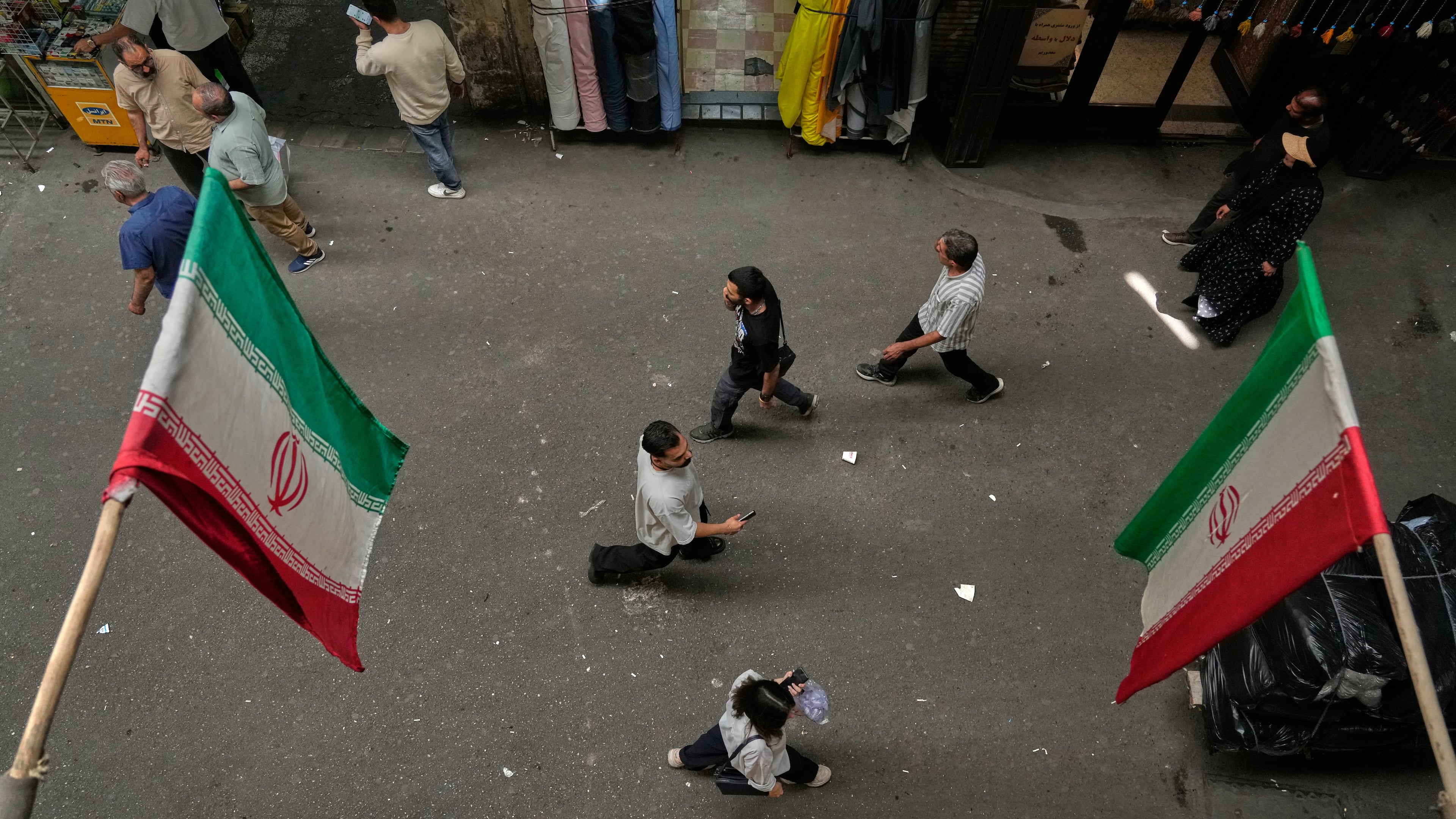 People walk as Iranian flags hang in the Grand Bazaar in Tehran, Sunday, May 3, 2026. (AP Photo/Vahid Salemi)