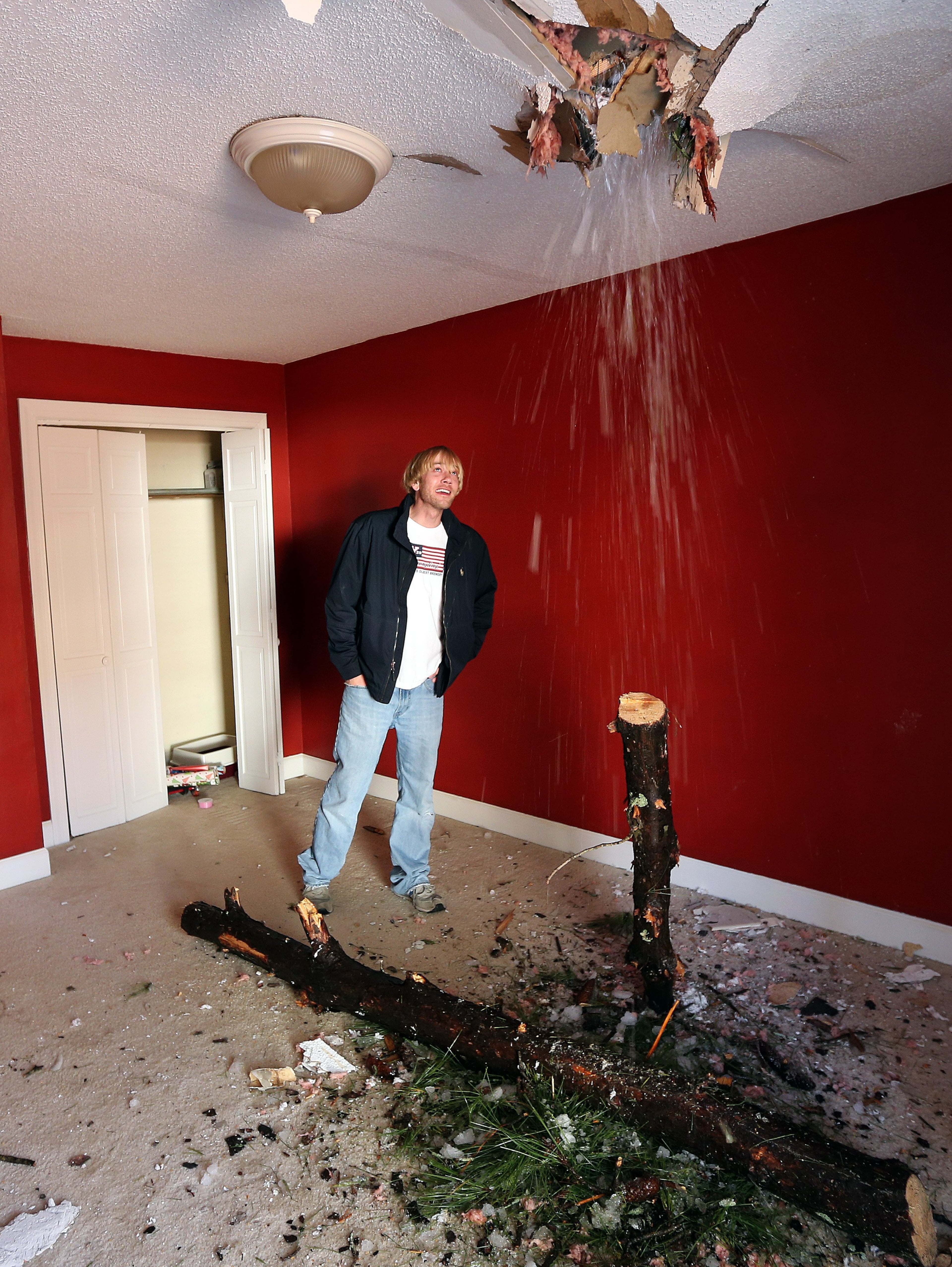 Spencer Pearson watches ice and snow fall into his guest bedroom Saturday morning February 15, 2014 after an ice-covered pine tree snapped and speared through the roof and ceiling and ended up embedded in the floor of the room.Pearson was staying at his girlfriend's house when the tree fell, so nobody was hurt. BEN GRAY / BGRAY@AJC.COM