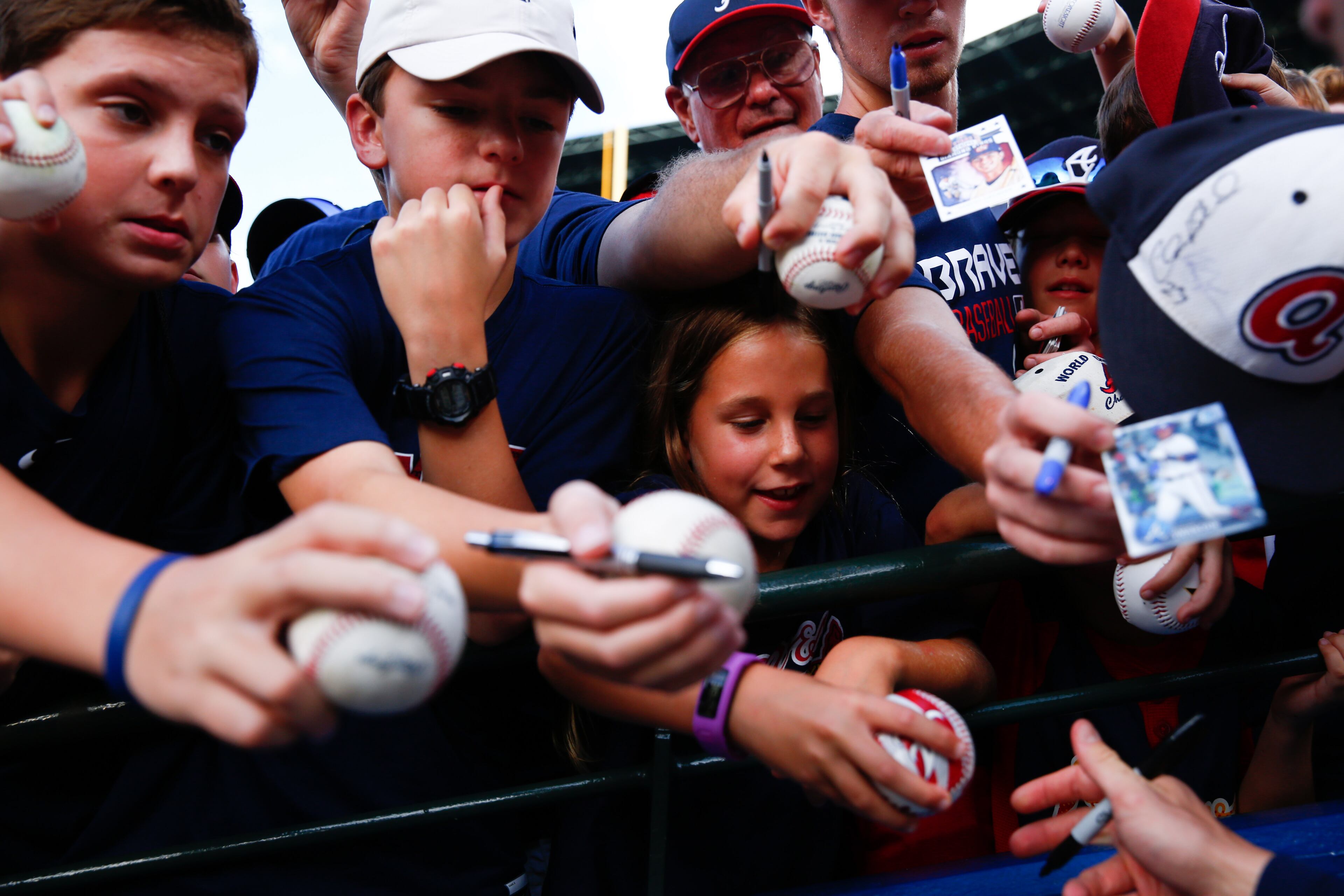 Caitlin Herhold, 9, center, gets a baseball signed by Dansby Swanson #2 of the Atlanta Braves prior to the game against the Washington Nationals at Turner Field on August 20, 2016 in Atlanta, Georgia. (Photo by Kevin Liles/Getty Images)