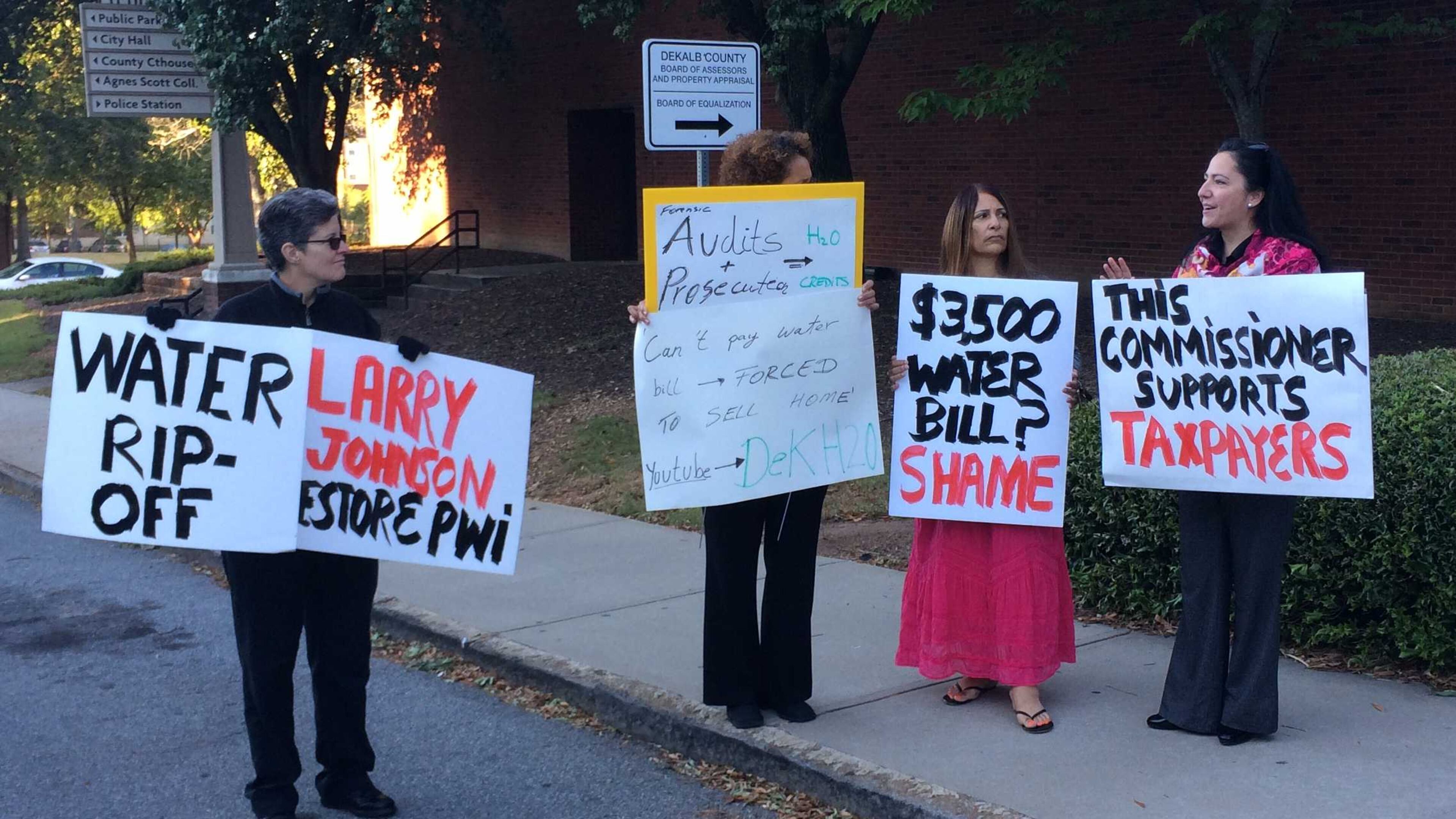 DeKalb County residents protest high water bills outside the county government center on Tuesday, Oct. 11, 2016. From left: Hope Lusignan, Anita Connor, Judy Knight and Commissioner Nancy Jester hold signs calling for the county government to fix the problem. MARK NIESSE / MARK.NIESSE@AJC.COM
