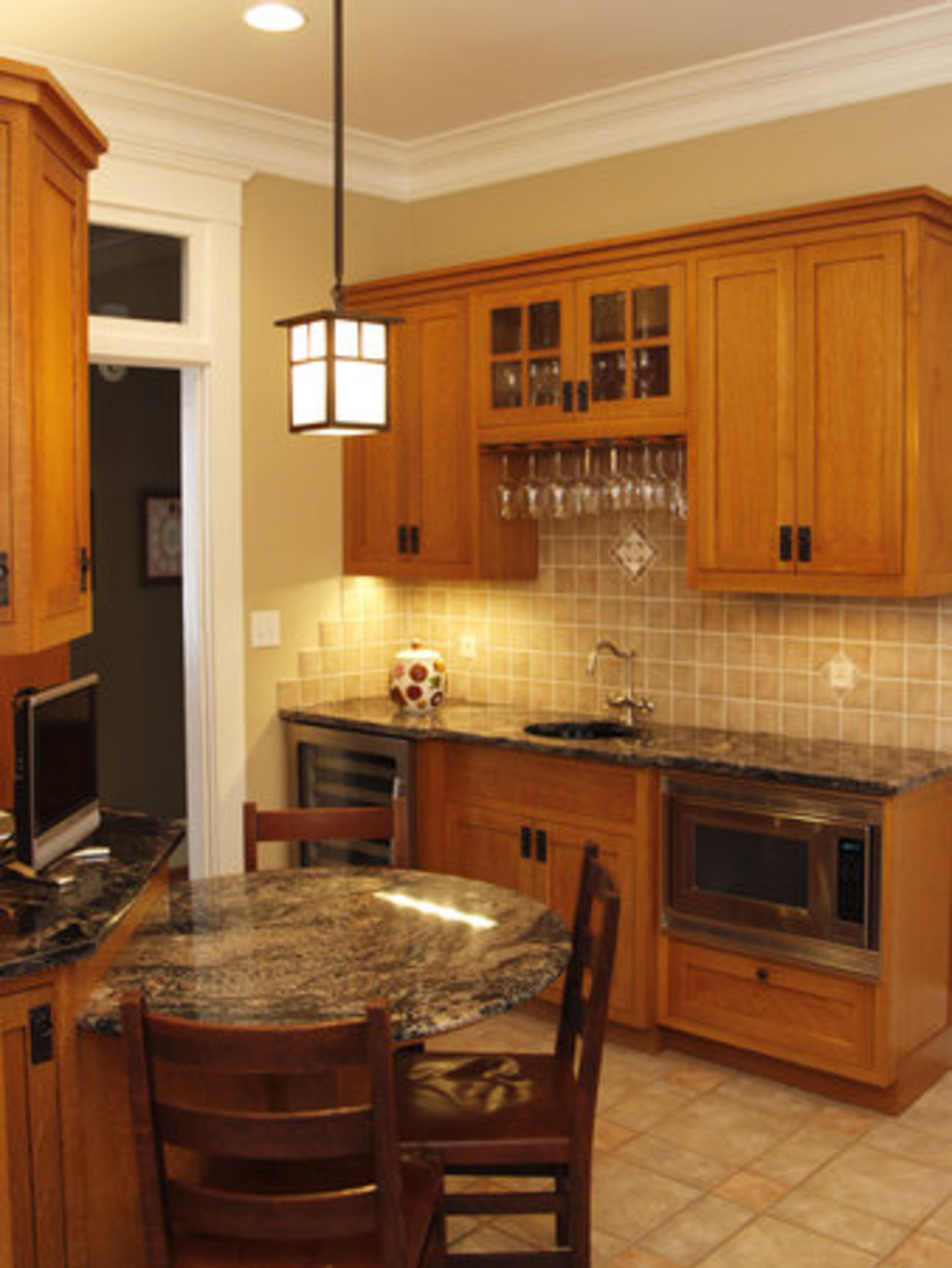 The kitchen features cabinets by James Henry for Southern Cabinet Design and custom-made hardware. Custom builds were done for a wine fridge and microwave to streamline the kitchen's aesthetic. Light fixtures are reproductions that retain the decor integrity of 1910.