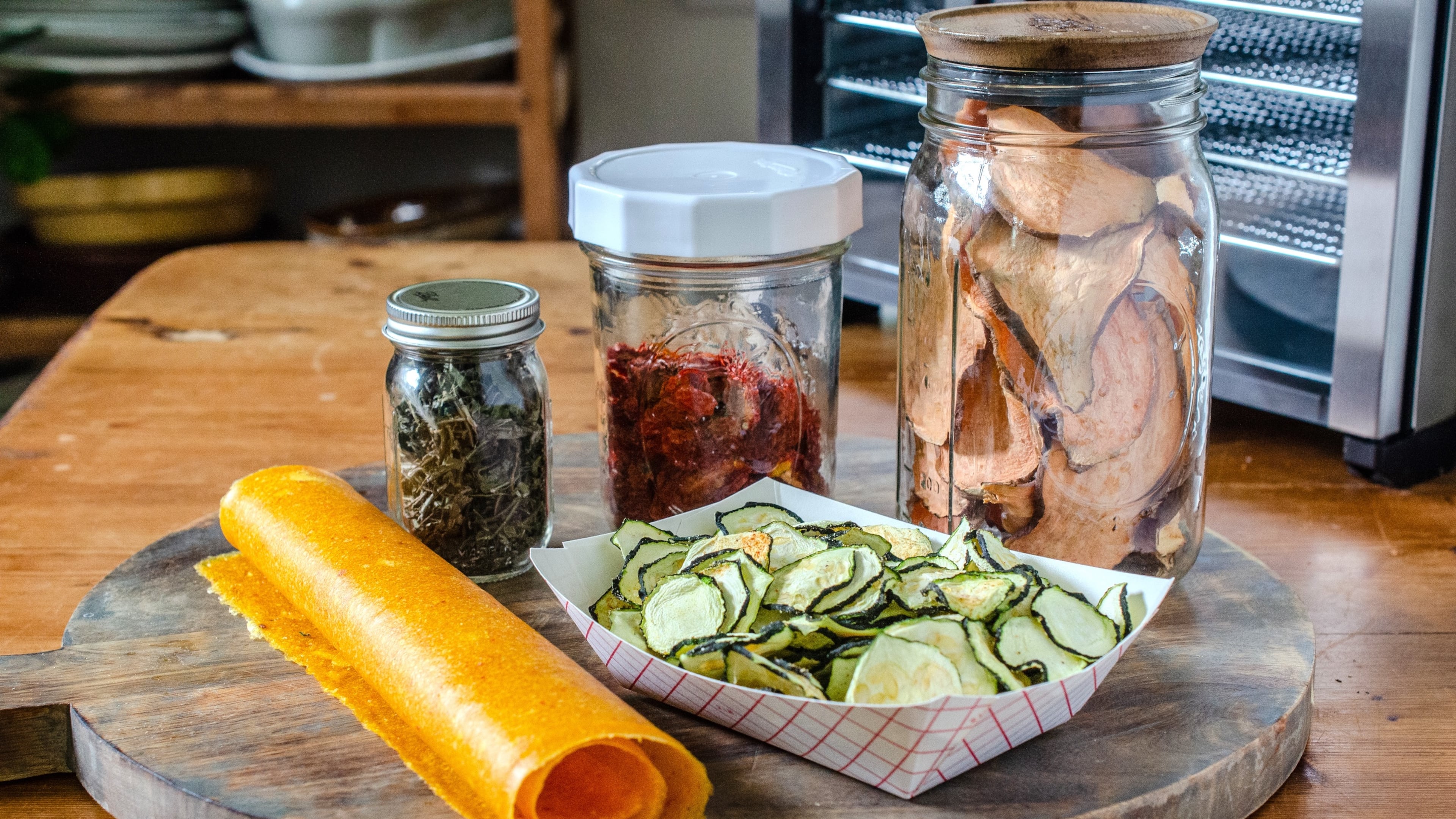 Dehydrating summer produce allows you to enjoy it during the season and beyond. Clockwise from top left: Italian Herb Seasoning Blend, Dehydrated Grape Tomatoes, Sweet Potato Dog Treats, Spiced Zucchini Chips and Mango Aleppo Fruit Leather. (Virginia Willis for the AJC)