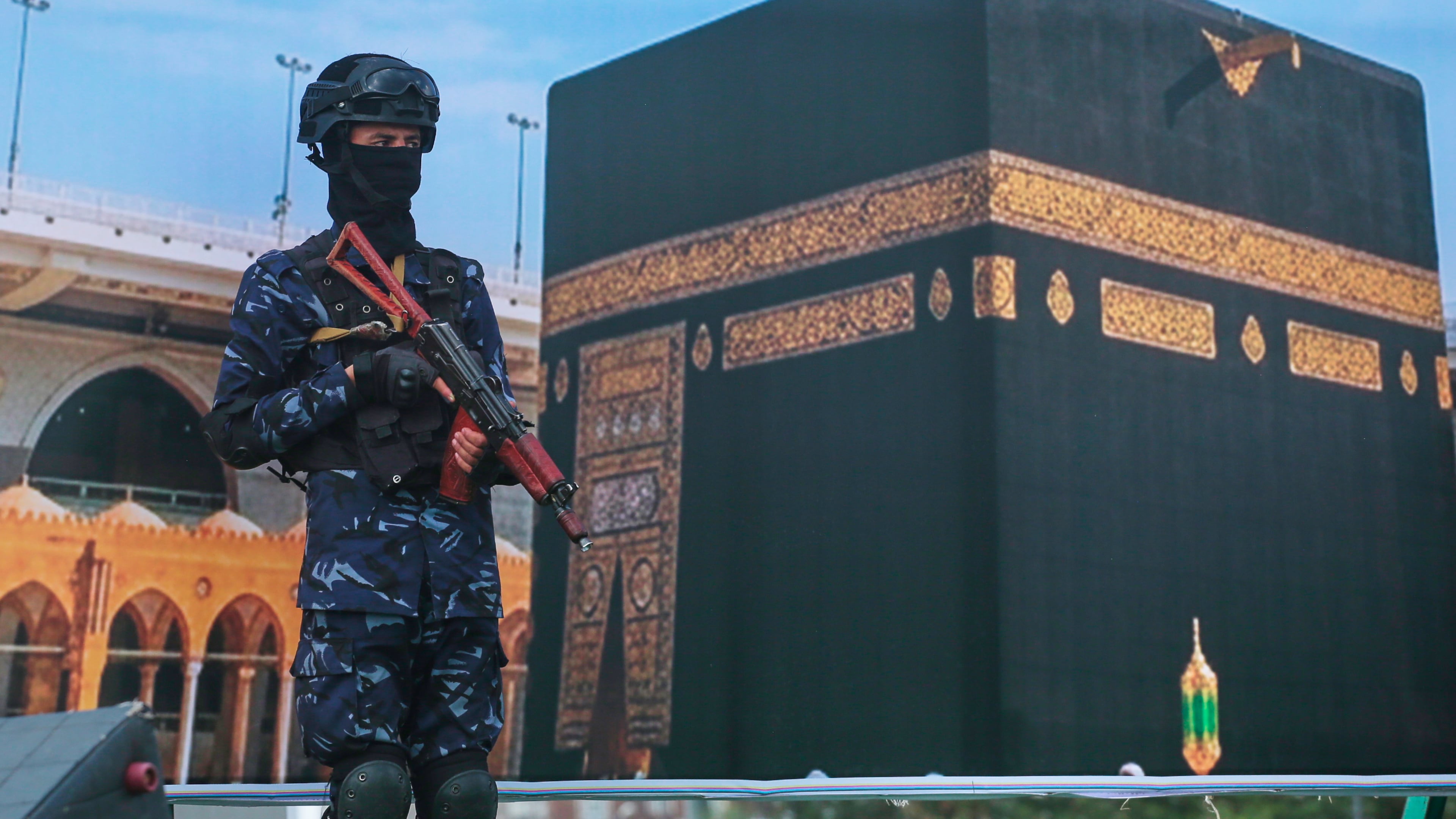 A soldier from Yemen's Houthi rebels stands in front of a giant banner of the Kaaba, during a rally to protest Saudi Arabia's accusation that the Houthis targeted Islam's holiest site in Sanaa, Yemen, Friday, Sept. 18, 2026. (AP Photo/Osamah Abdulrahman)
