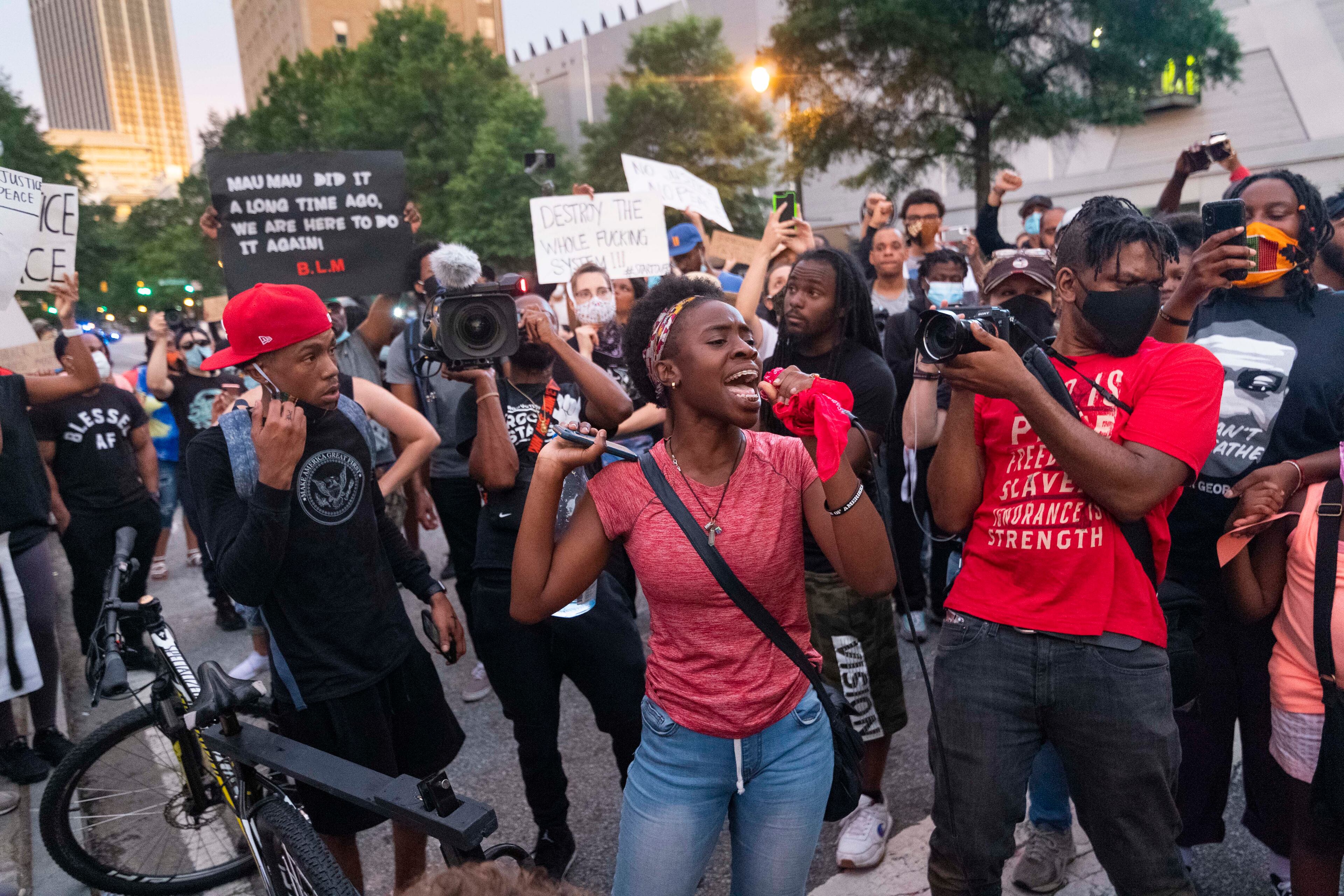 Tiffany Swaby grabs a microphone while people are dancing to stop them and say there is still a long way to go to see improvement, during protests Saturday, June 6, 2020, in Atlanta. Protesters were demonstrating against the death of George Floyd at the knee of Minneapolis police. JOHN AMIS FOR THE ATLANTA JOURNAL-CONSTITUTION