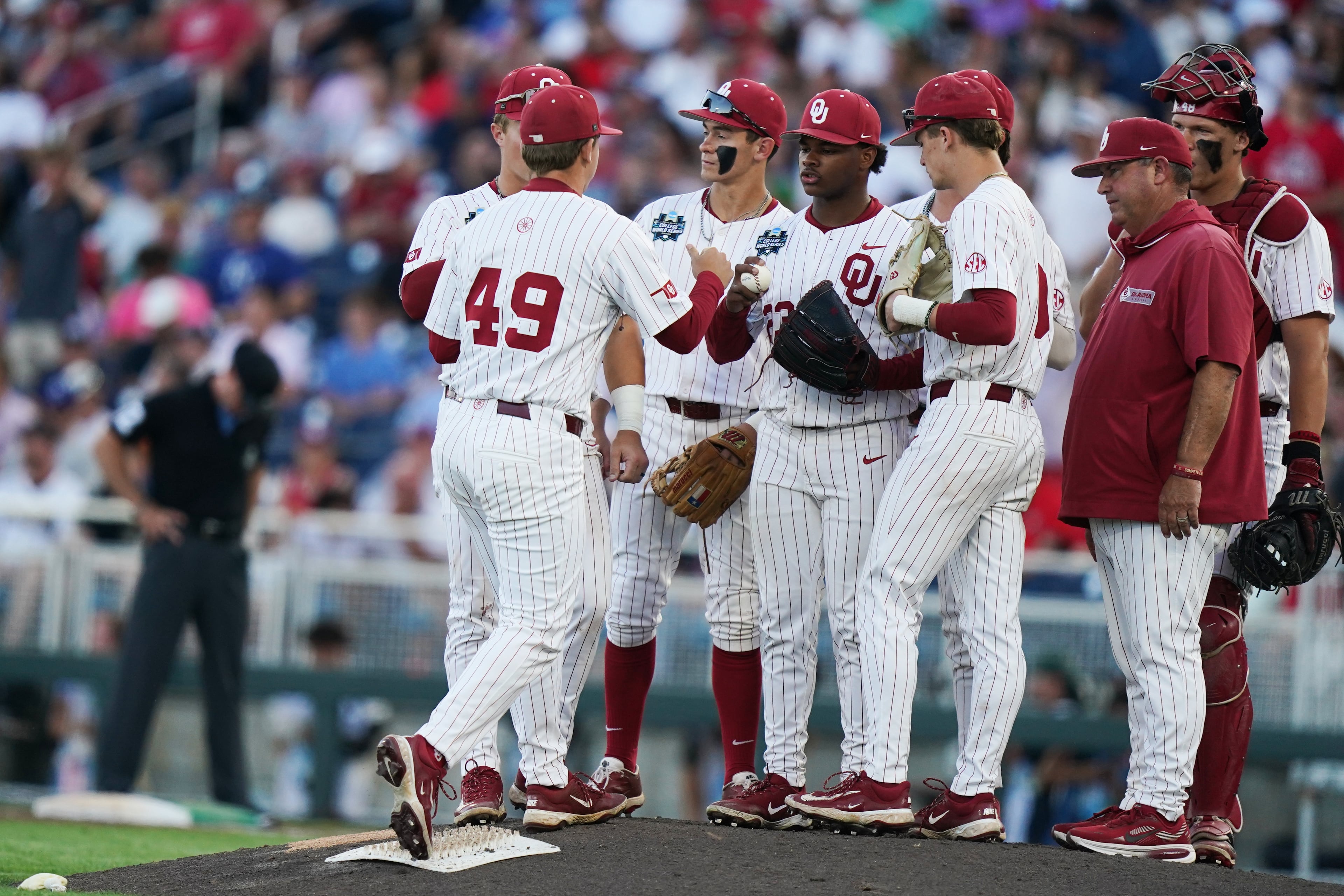 Oklahoma starting pitcher Xander Mercurius (center) hands the ball over to reliever Jackson Cleveland (left) during their College World Series game against Georgia on Monday, June 15, 2026, in Omaha, Neb. (Vera Nieuwenhuis/AP)