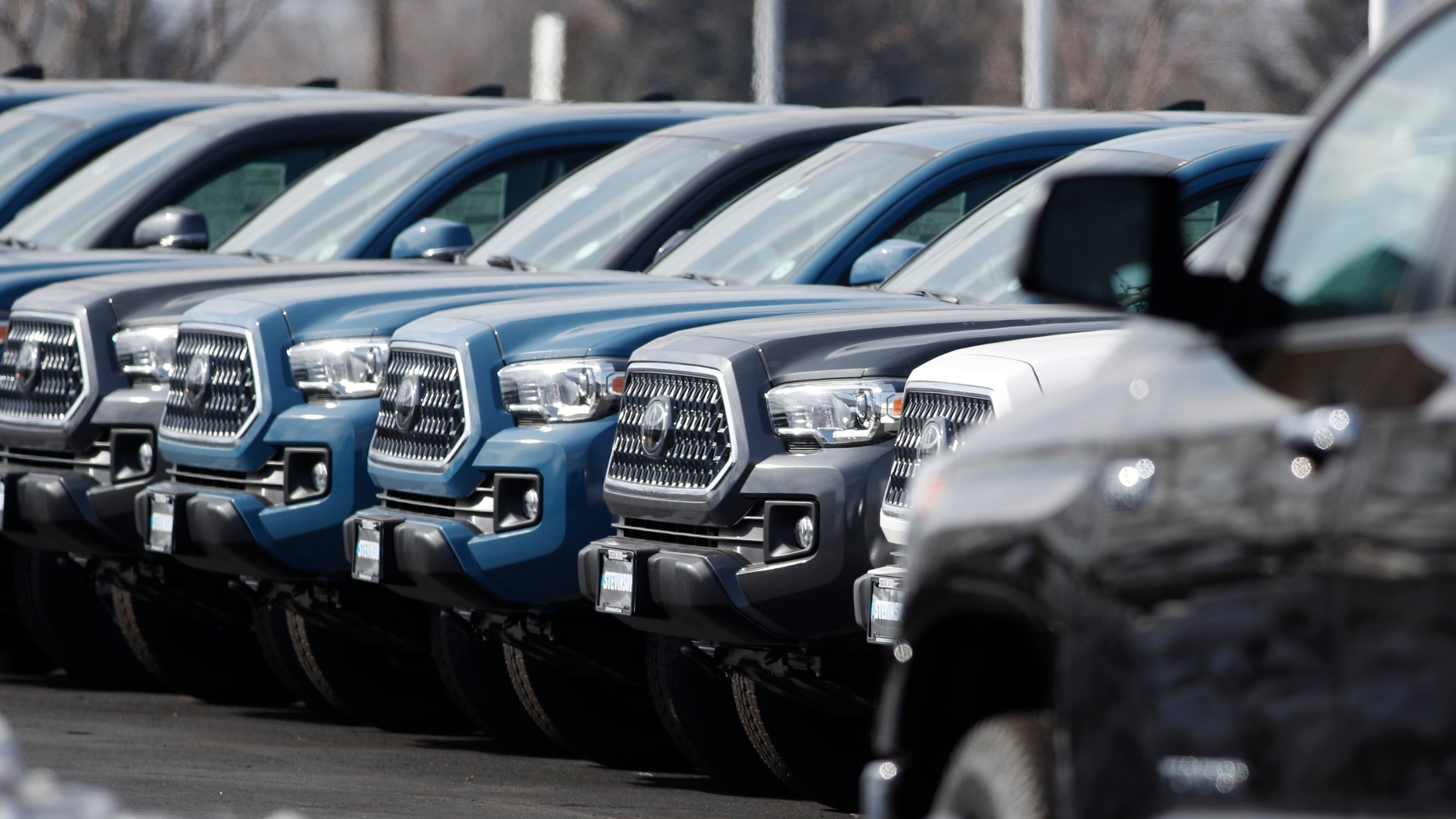 A long row of 2019 Tacoma pickup trucks sits at a Toyota dealership in Lakewood, Colo. Toyota has settled a lawsuit from the wife of an Atlanta man who died of carbon monoxide poisoning after unwittingly leaving his 2017 Tacoma idling in the garage attached to their home. Toyota implemented automatic engine shut-off in its vehicles in 2020. (David Zalubowski/AP 2019)