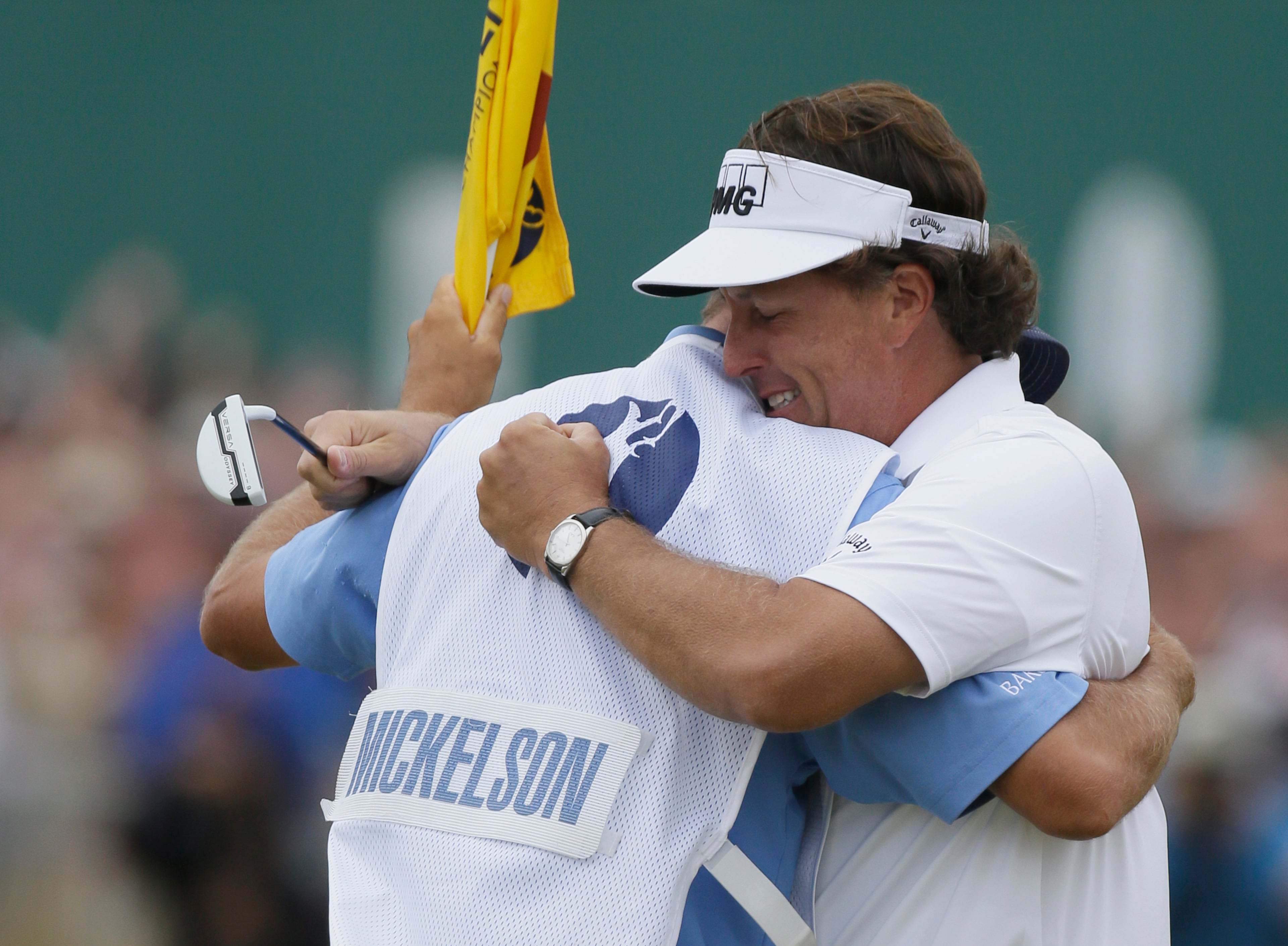 Phil Mickelson of the United States celebrates after his final putt on the 18th green with his caddie Jim Mackay during the final round of the British Open Golf Championship at Muirfield, Scotland, on July 21, 2013.