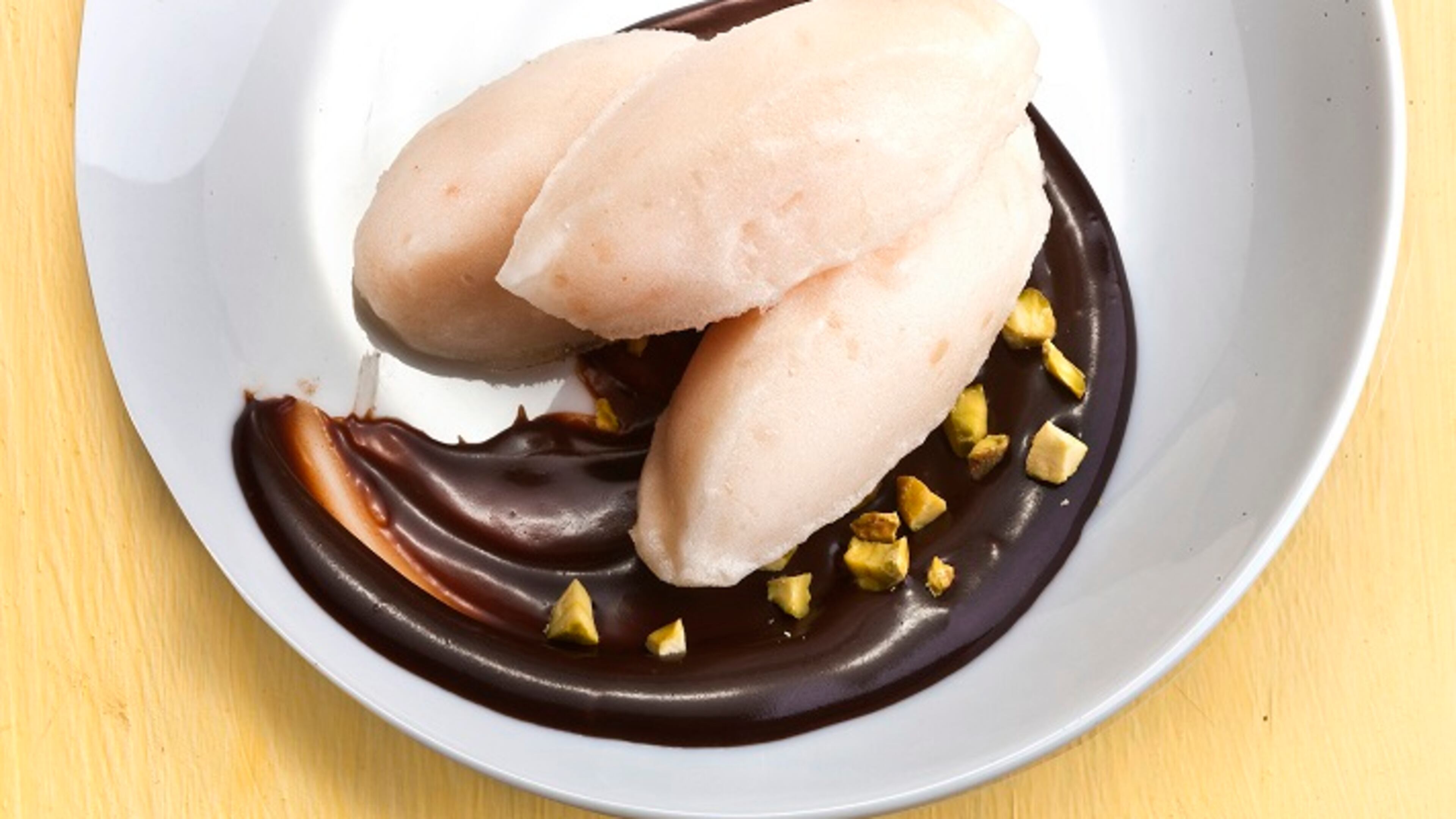 A quenelle, a shape reminiscent of an American football, is an elegant way to serve ice cream. Some ganache finishes the plate. (Bill Hogan/Chicago Tribune/TNS)