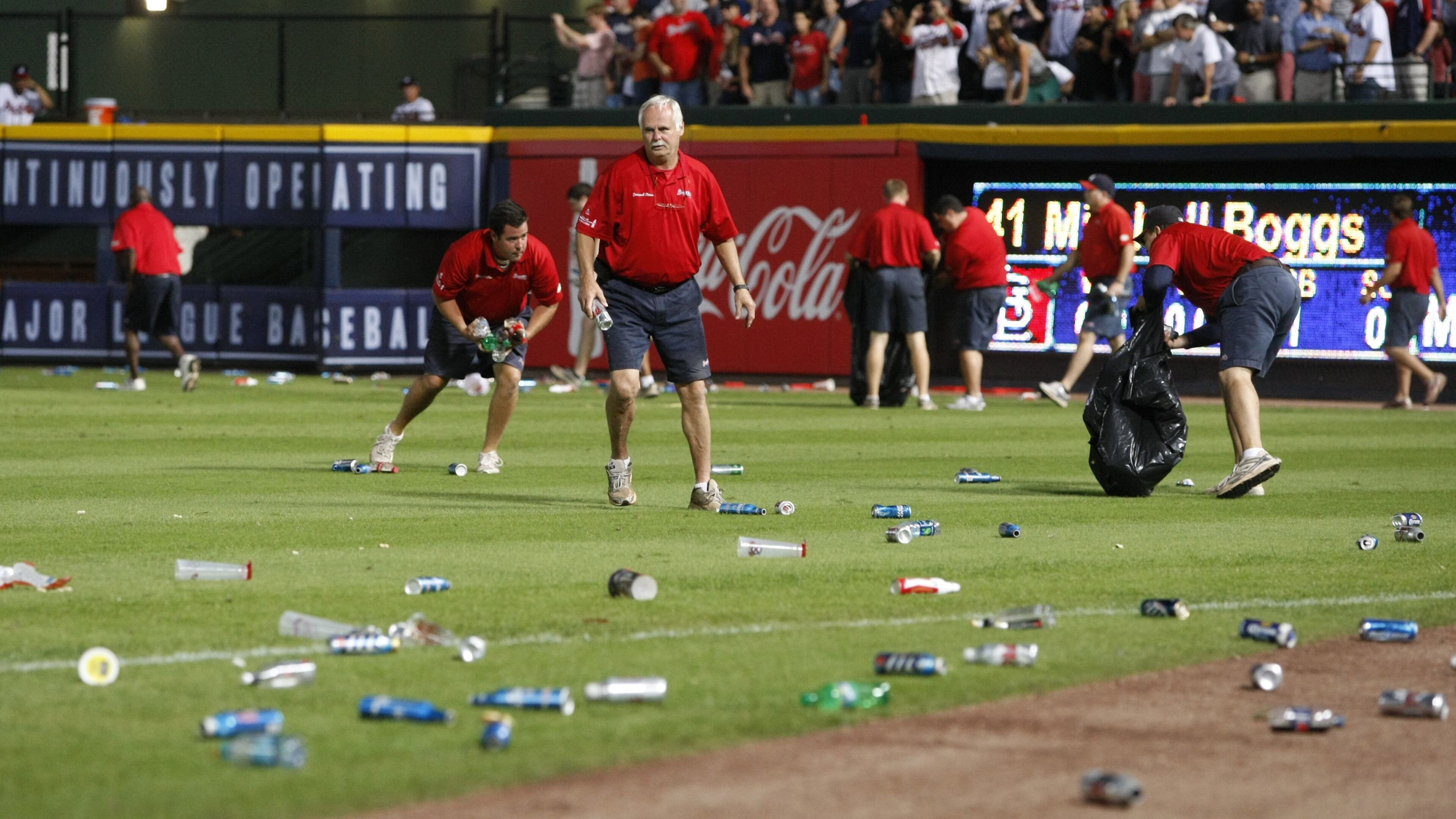 Atlanta Braves ground crew members clean trash off the field after fans littered the area protesting an infield fly rule call on Andrelton Simmons in the eighth inning of the National League wild card game against the St. Louis Cardinals at Turner Field in Atlanta on Friday, Oct. 5, 2012. CURTIS COMPTON / CCOMPTON@AJC.COM