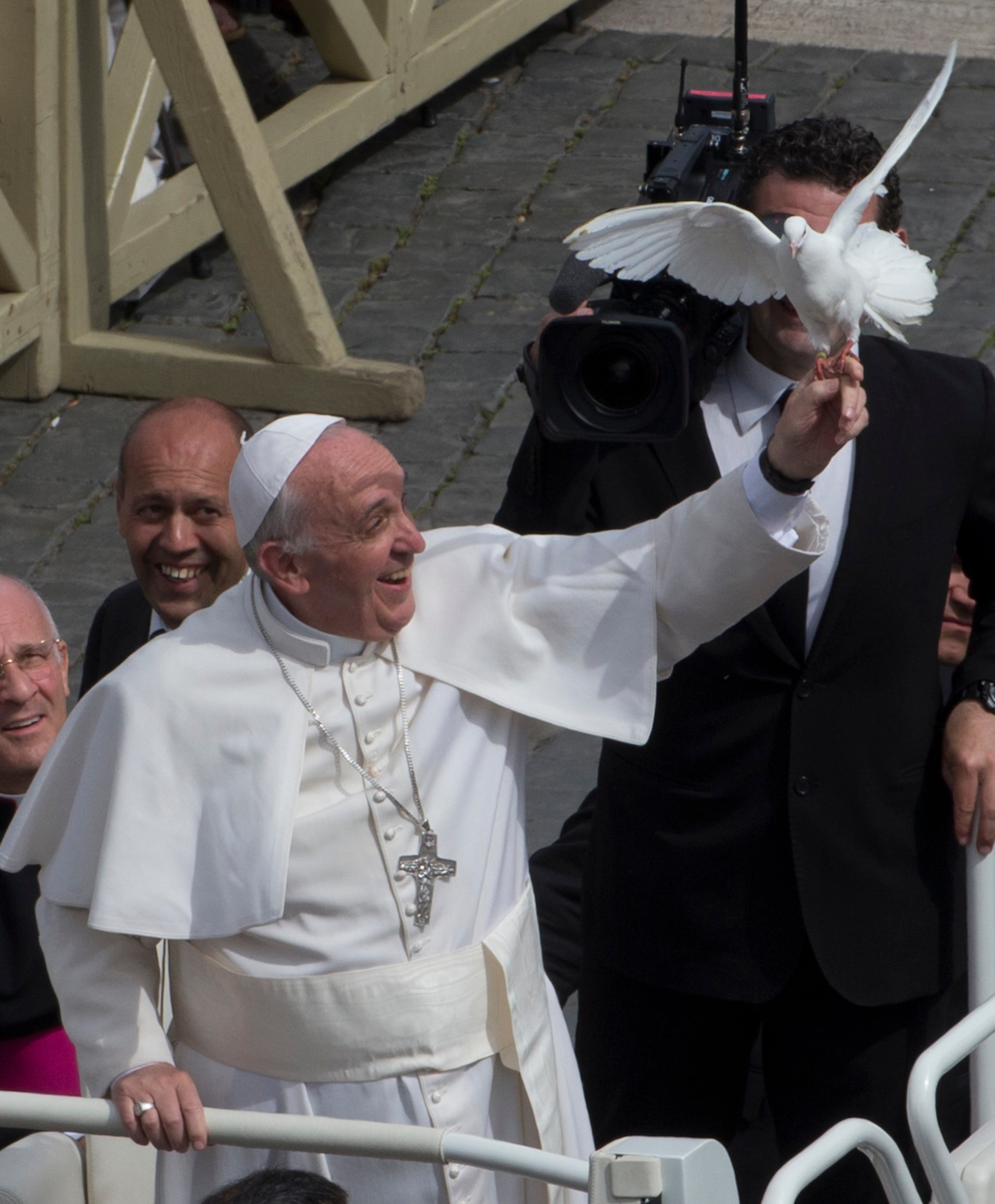 Pope Francis frees a dove during his weekly general audience in St. Peter Square at the Vatican, Wednesday, May 15, 2013. As Francis toured the square in his open-topped popemobile at his Wednesday audience with the public, someone at the edge of the crowd thrust a white bird cage at him. Looking puzzled, his security detail took the cage, containing a pair of white doves, and handed it to Francis. Without hesitation, the pope opened the cage door, thrust a hand inside and extracted one dove, and with a flick of his hand, sent the bird flying over the square. (AP Photo/Alessandra Tarantino)