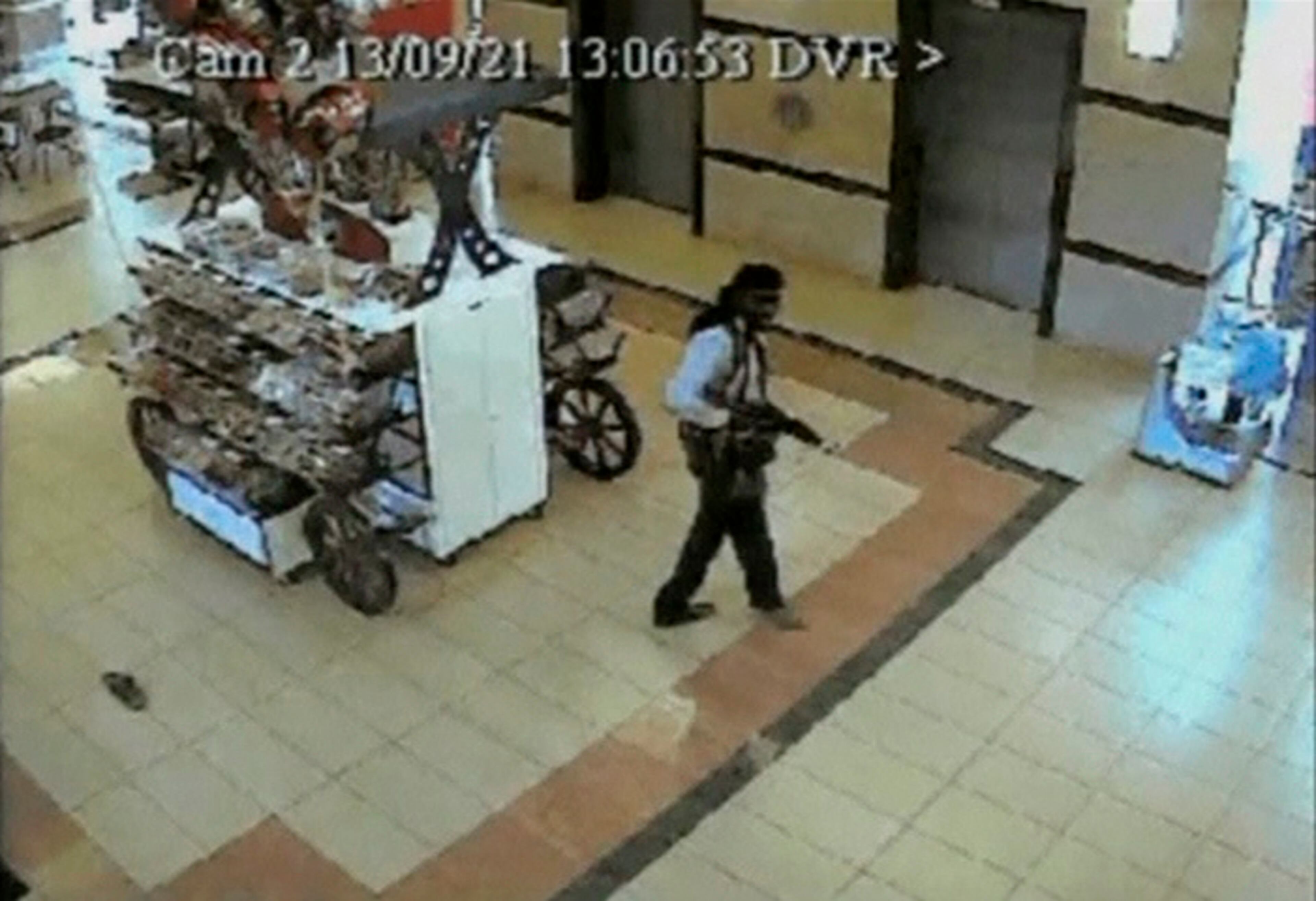 A gunman walks next to a stall during an attack, inside the Westgate shopping mall in this still frame taken from video footage by security cameras inside the mall in Nairobi and released to Reuters on October 17, 2013. Chilling video footage obtained by Reuters show the moment gunmen entered the Nairobi Westgate mall on September 21, 2013 and randomly shot down shoppers in the supermarket. In the four day siege that followed, about 60 people died and more are still missing, with reports on October 17, 2013 that some body parts were recovered from the collapsed section of the mall. REUTERS/Reuters TV (KENYA - Tags: CIVIL UNREST CRIME LAW)