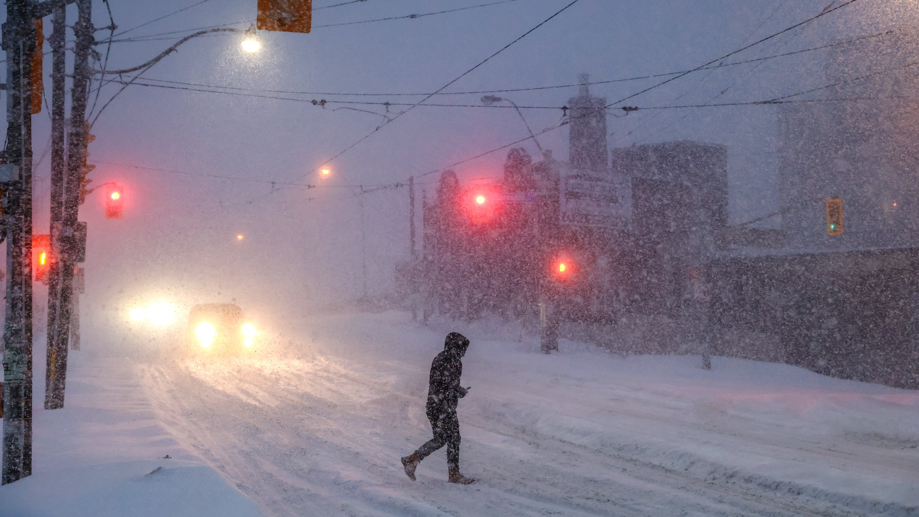 People walk through downtown Toronto as a winter storm moves through the region, Sunday, Jan. 25, 2026. (Cole Burston/The Canadian Press via AP)