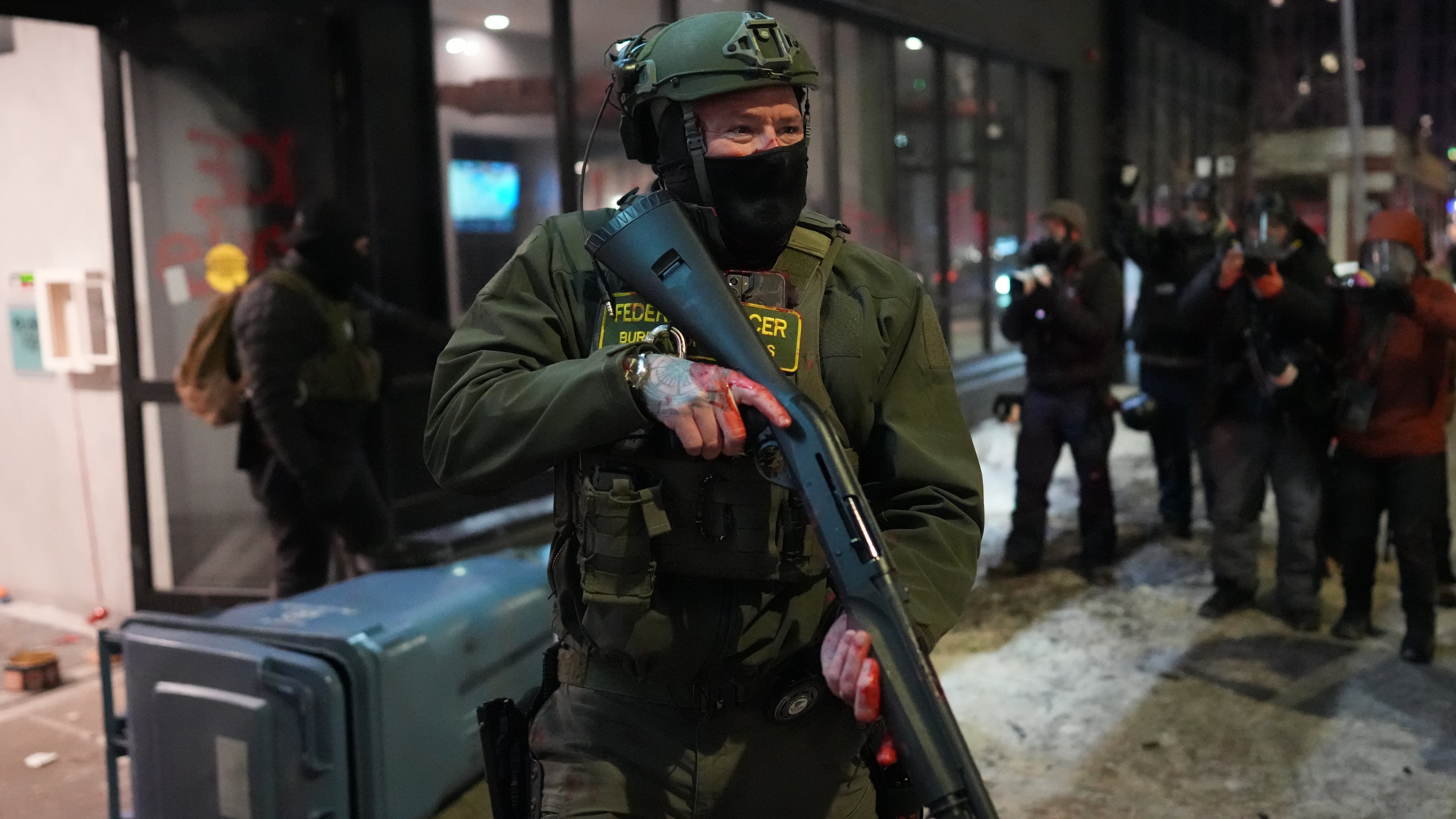 A federal agent stands guard near a hotel during a noise demonstration protest in response to federal immigration enforcement operations in the city Sunday, Jan. 25, 2026, in Minneapolis. (AP Photo/Adam Gray)