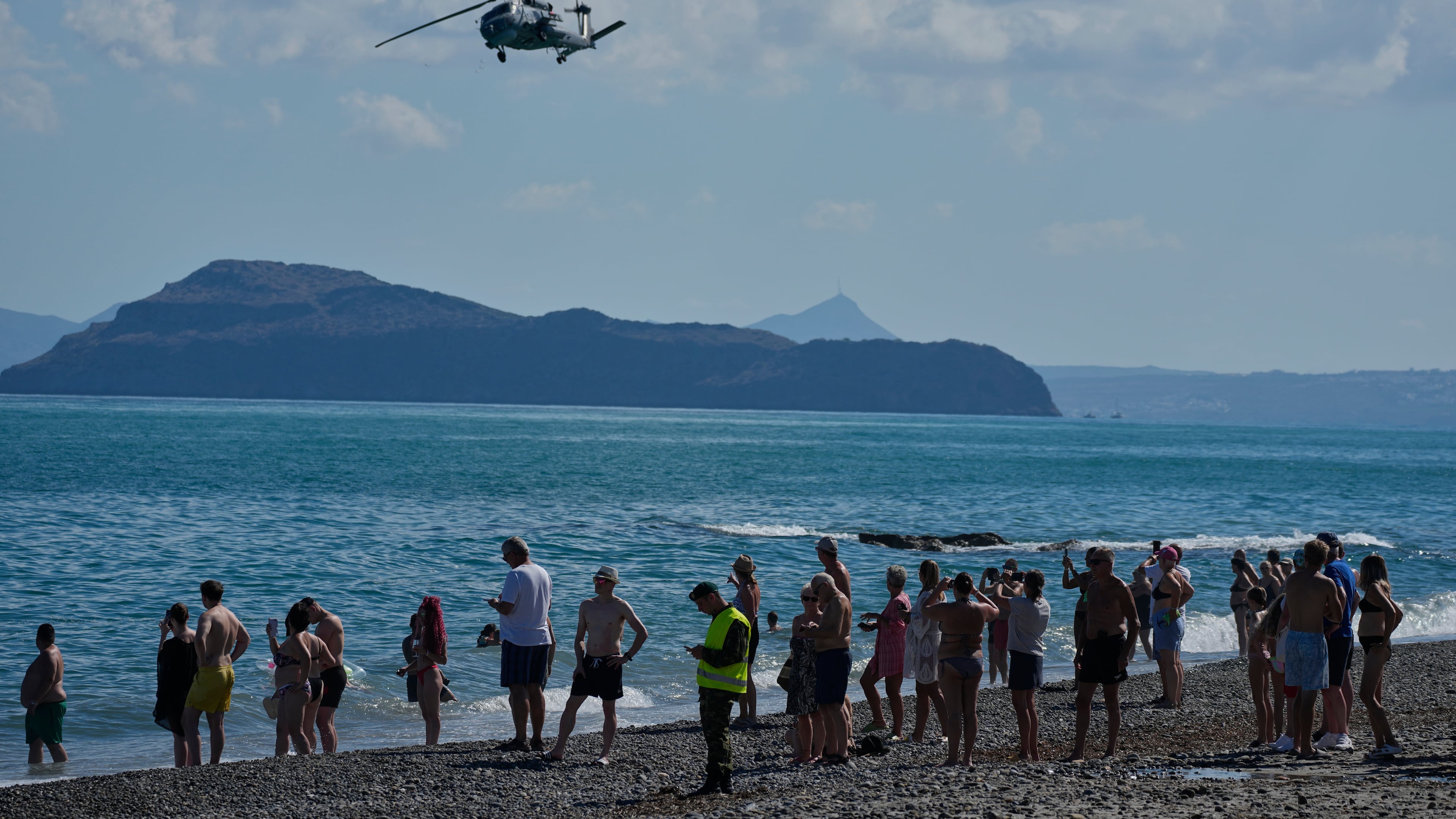 Tourists from nearby hotels watch a military helicopter fly overhead during Medusa 15, a multinational military exercise led by Greece and Egypt, at Maleme on the Greek island of Crete, Friday, Sept. 18, 2026. (AP Photo/Thanassis Stavrakis)