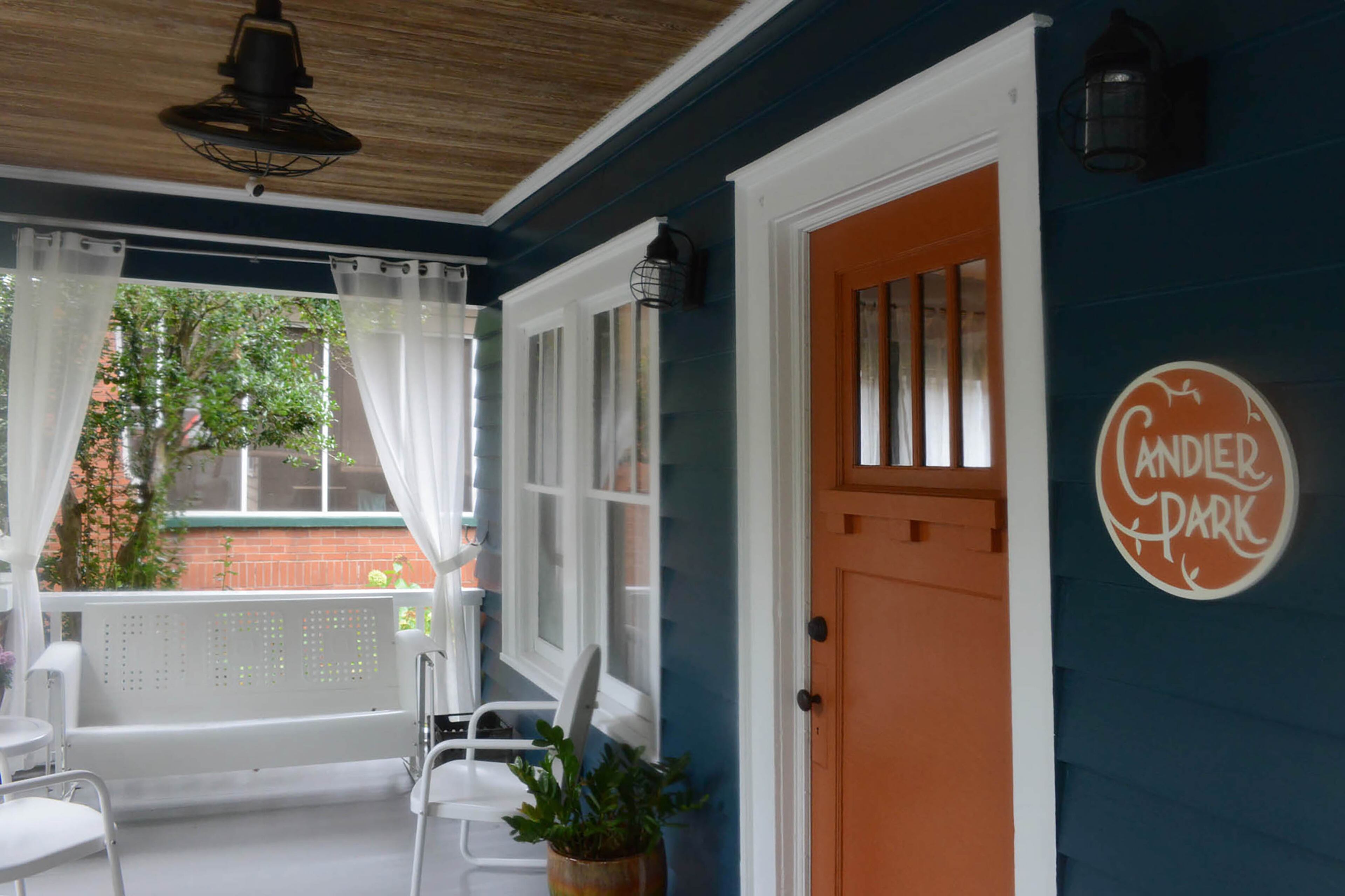 A burnt orange neighborhood plaque is a strong contrast with the exterior, which is painted Benjamin Moore Newburg Green. To prepare for the neighborhood's fall Tour of Homes, homeowner Chris Erickson renovated the porch, which included removing the screen and adding white furniture from Hayneedle.com. Christopher Oquendo/AJC FILE