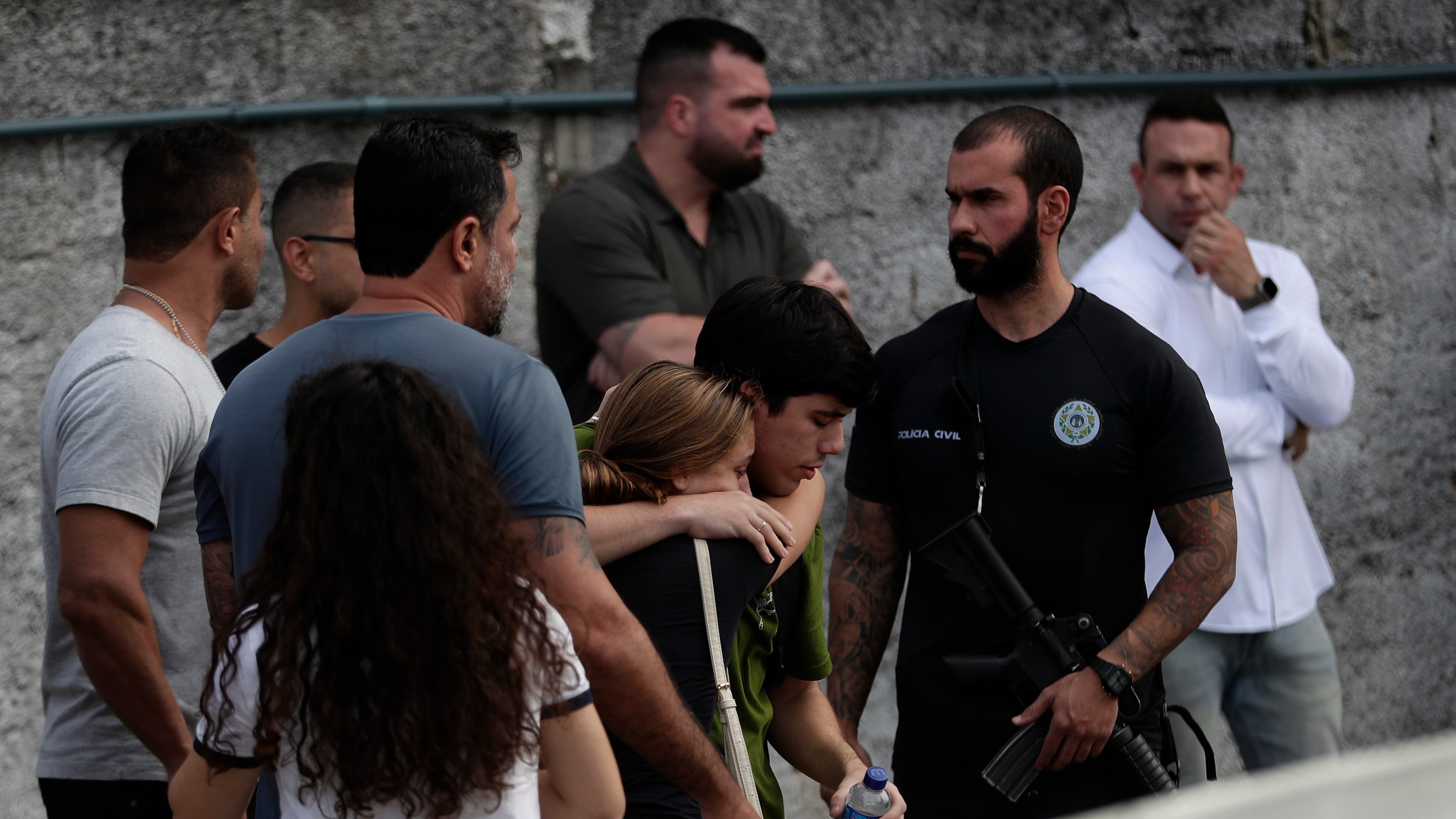 People comfort each other near the site where two helicopters reportedly collided in midair and crashed into a car dealership parking lot in Rio de Janeiro, Brazil, Sunday, June 14, 2026. (AP Photo/Bruna Prado)