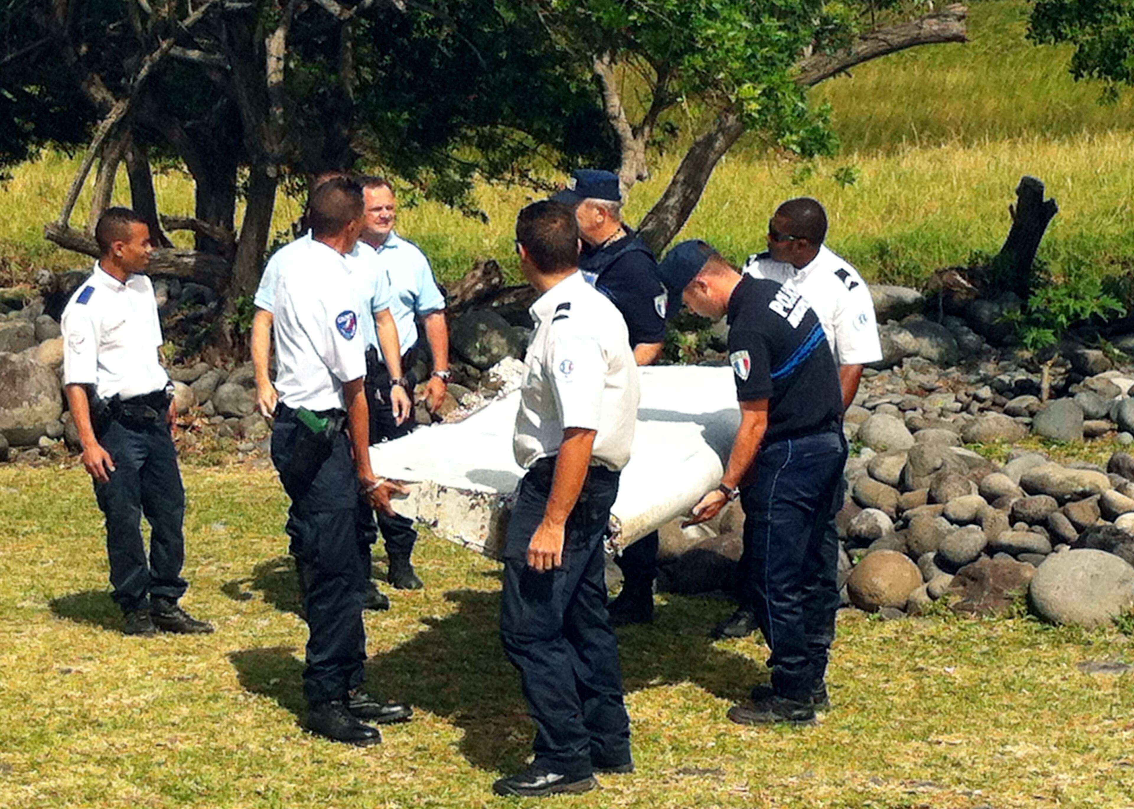 Police and gendarmes carry a piece of debris from an unidentified aircraft found in the coastal area of Saint-Andre de la Reunion, in the east of the French Indian Ocean island of La Reunion, on July 29, 2015. The two-metre-long debris, which appears to be a piece of a wing, was found by employees of an association cleaning the area and handed over to the air transport brigade of the French gendarmerie (BGTA), who have opened an investigation. An air safety expert did not exclude it could be a part of the Malaysia Airlines flight MH370, which went missing in the Indian Ocean on March 8, 2014. (Photo: YANNICK PITOU/AFP/Getty Images)