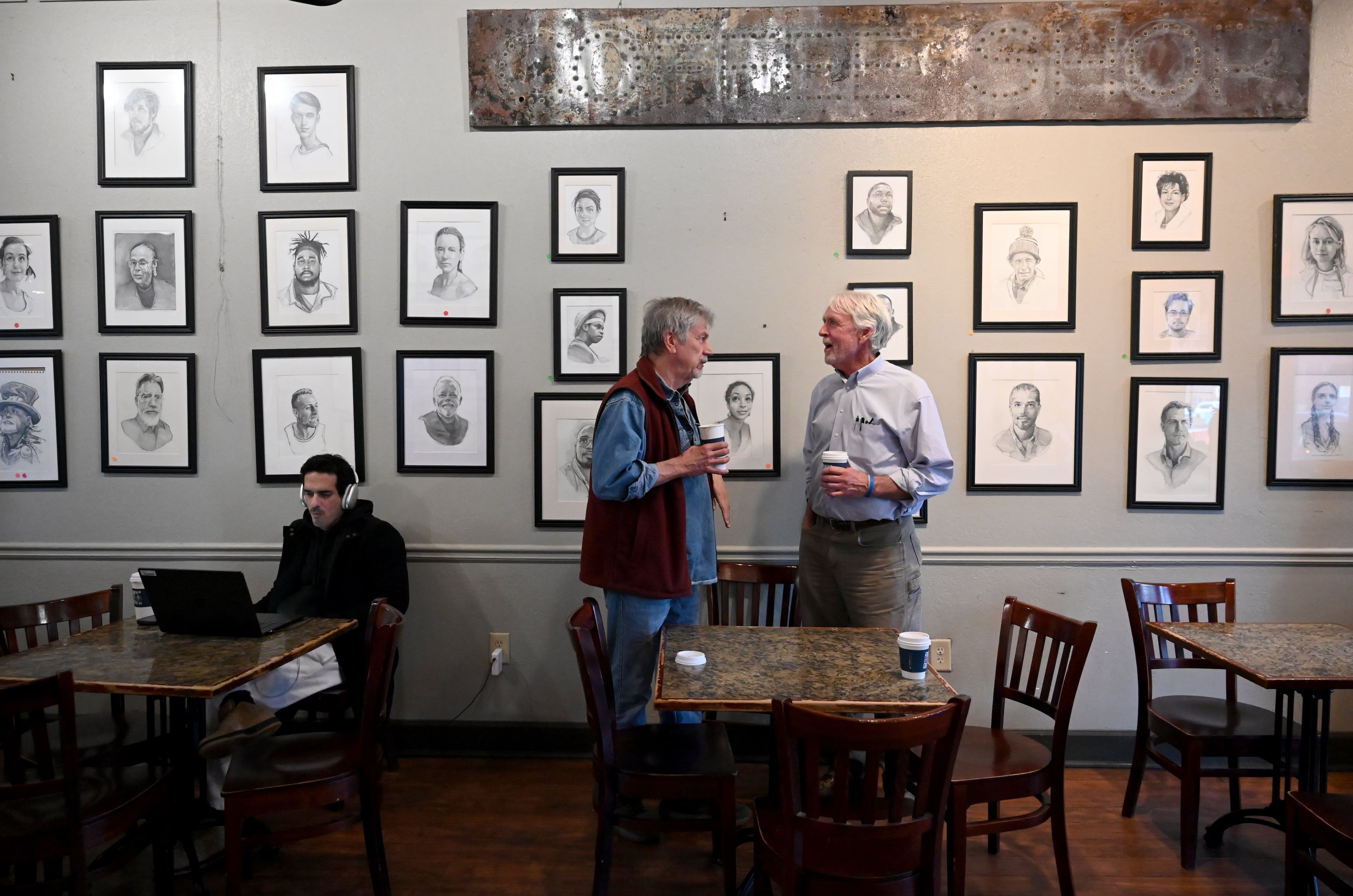 Allen Levi (right) talks with his portrait-artist friend Garry Pound at Fountain City Coffee, where Pound’s portraits are displayed on the walls. (Hyosub Shin/AJC)