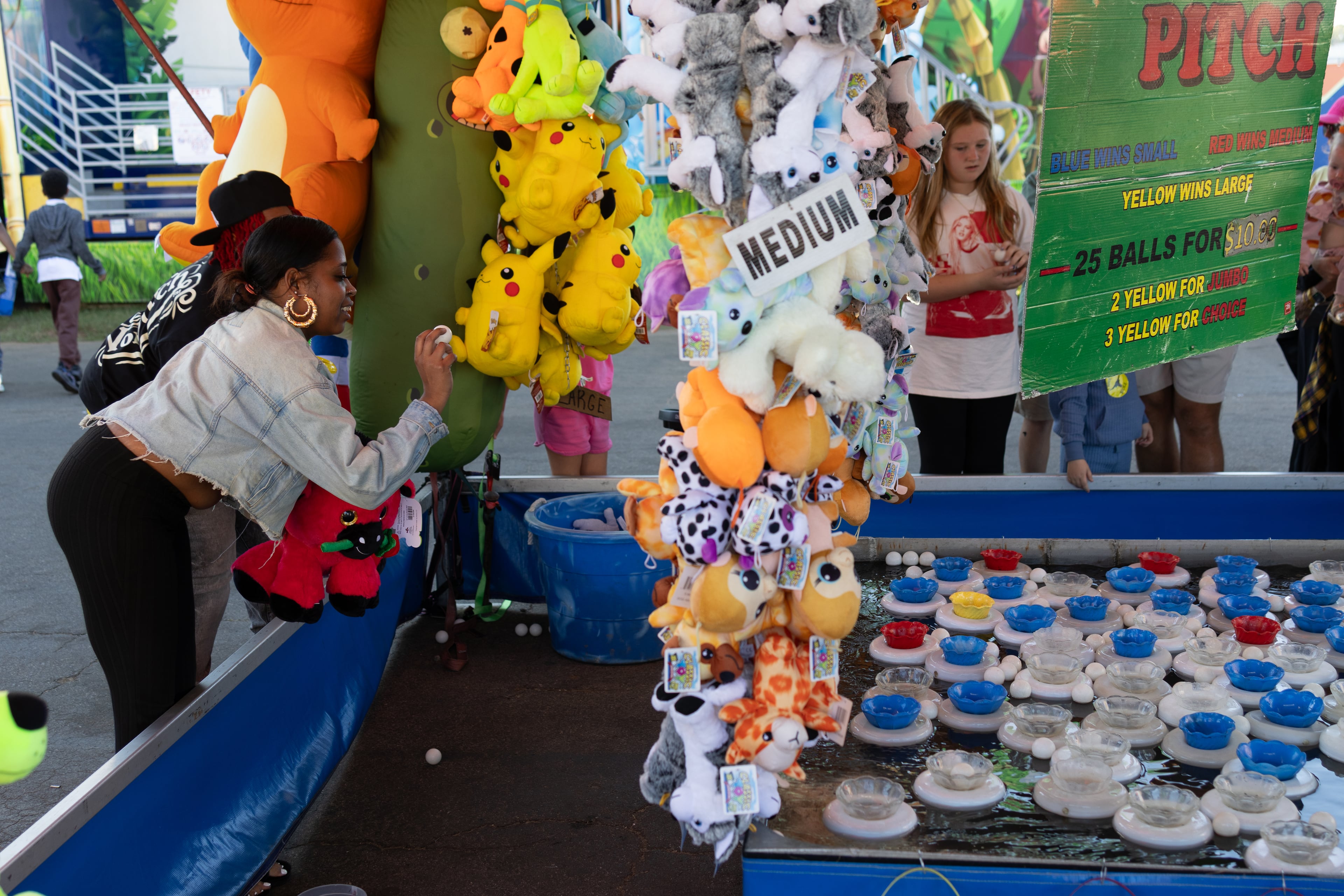 Jasmine Myers gets her throwing arm positioned to toss a ping pong ball into one of the targets at the 37th annual Georgia National Fair on Saturday, October 17, 2026. This is Myers' first time at the fair, and she had already won multiple prizes early in the evening. (Wesley Webb/UGA Photojournalism Workshop)