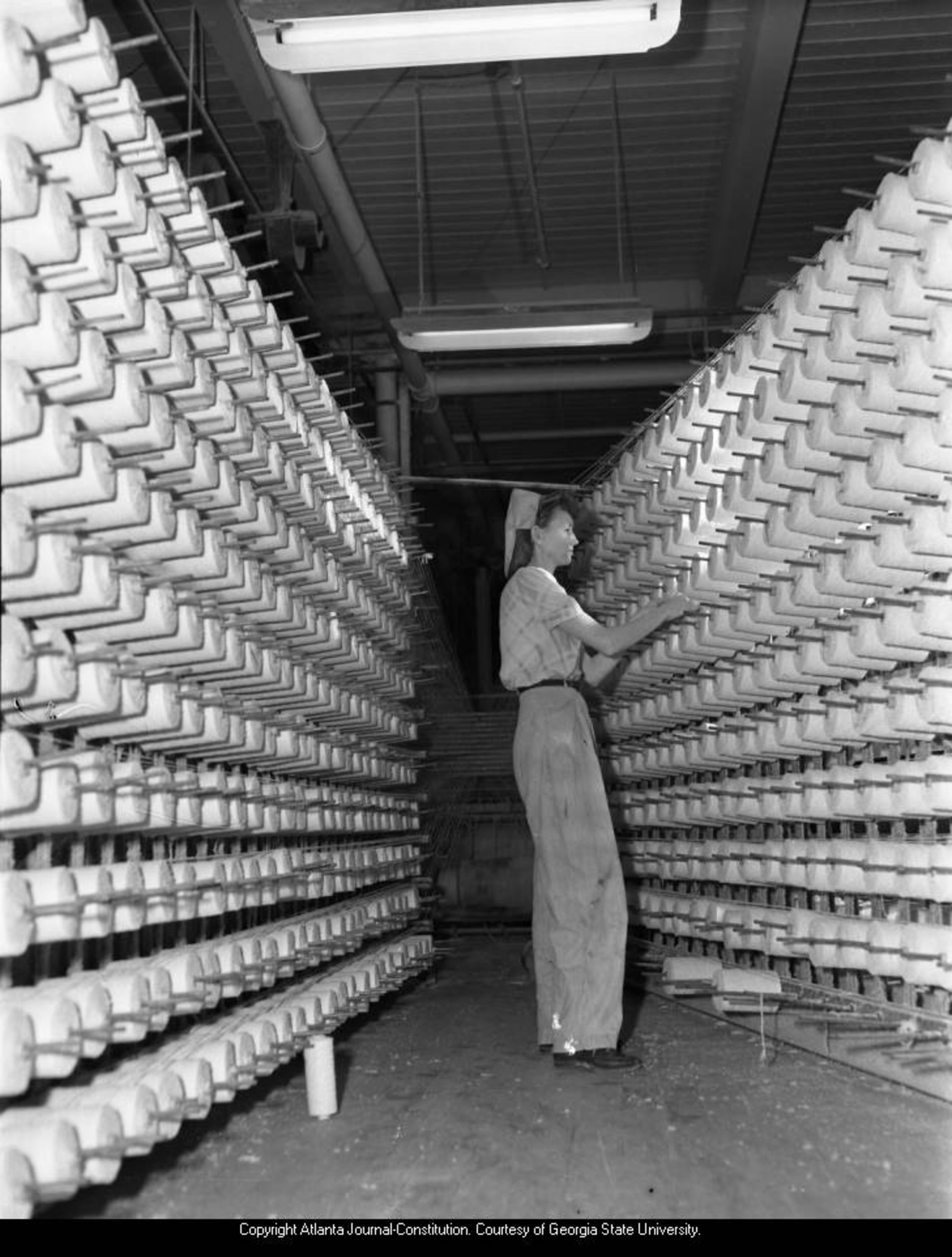 1947 -- A female industrial worker prepares spools for an asbestos fabric loom in Hogansville. AJC PHOTO ARCHIVES