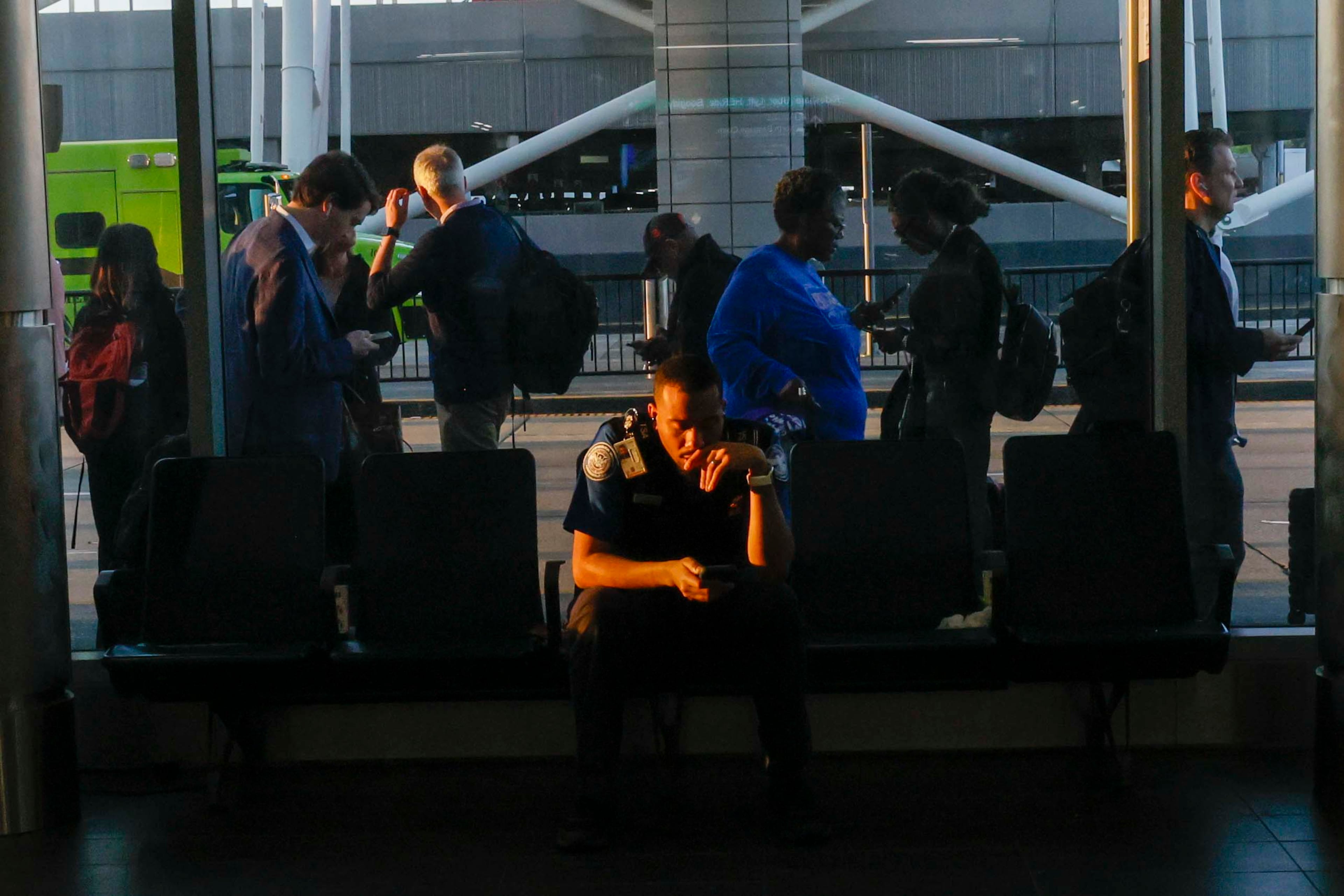 A TSA agent takes a break as travelers line up on the sidewalks for TSA security checks early Monday morning at Hartsfield-Jackson Atlanta International Airport during the partial government shutdown on March 23, 2026. TSA officers have been working without pay for weeks amid the shutdown. (Miguel Martinez/AJC)
