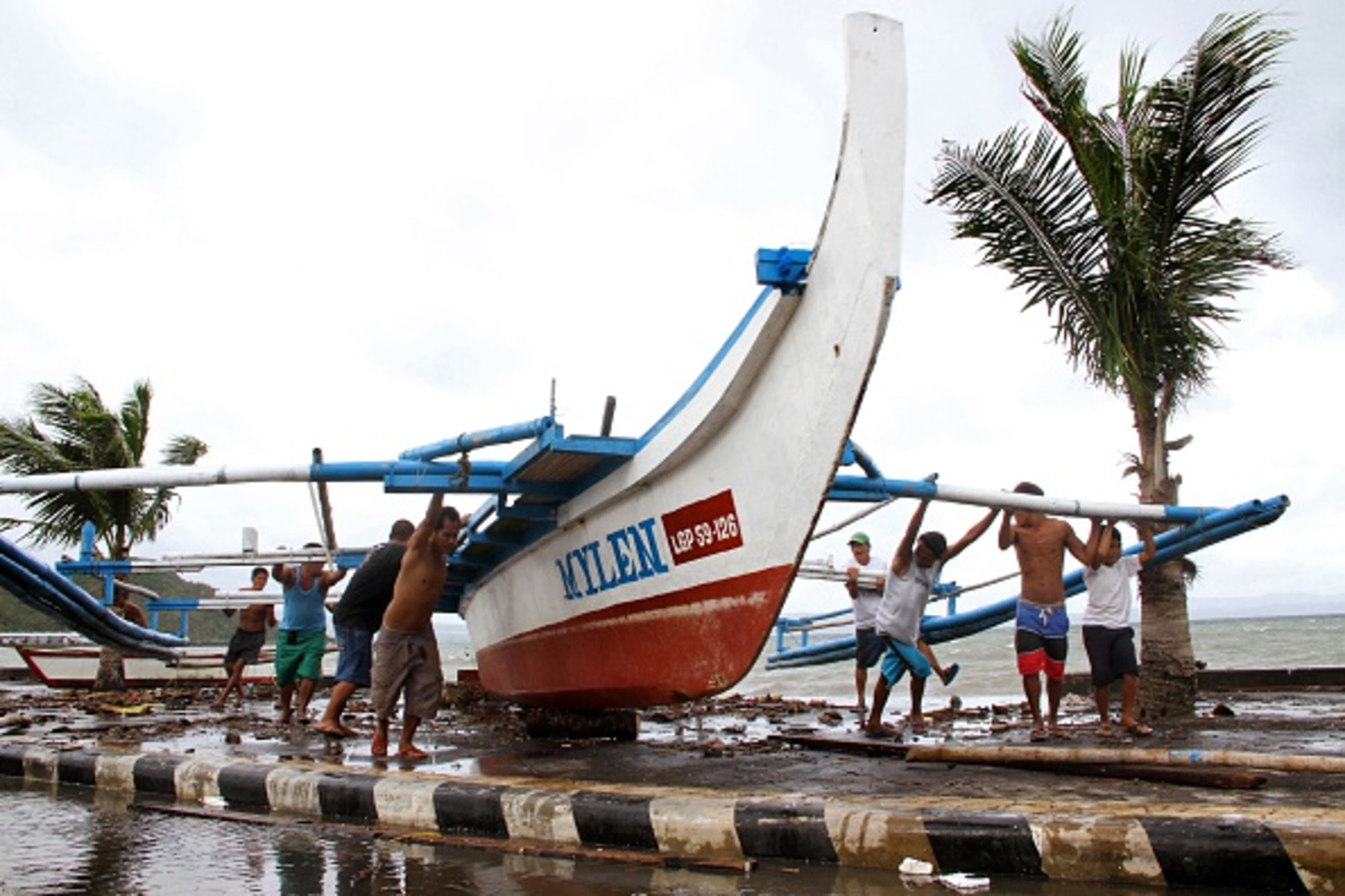 Fishermen carry thier outrigger to higher ground in Legazpi City, south of Manila on December 5, 2014, ahead of the landfall of Typhoon Hagupit. Thousands of people in the Philippines sought shelter in churches, schools and other makeshift evacuation centres on December 5 as monster Typhoon Hagupit bore down on the disaster-weary nation. AFP PHOTO / Charism SAYAT (Photo credit should read Charism SAYAT/AFP/Getty Images)